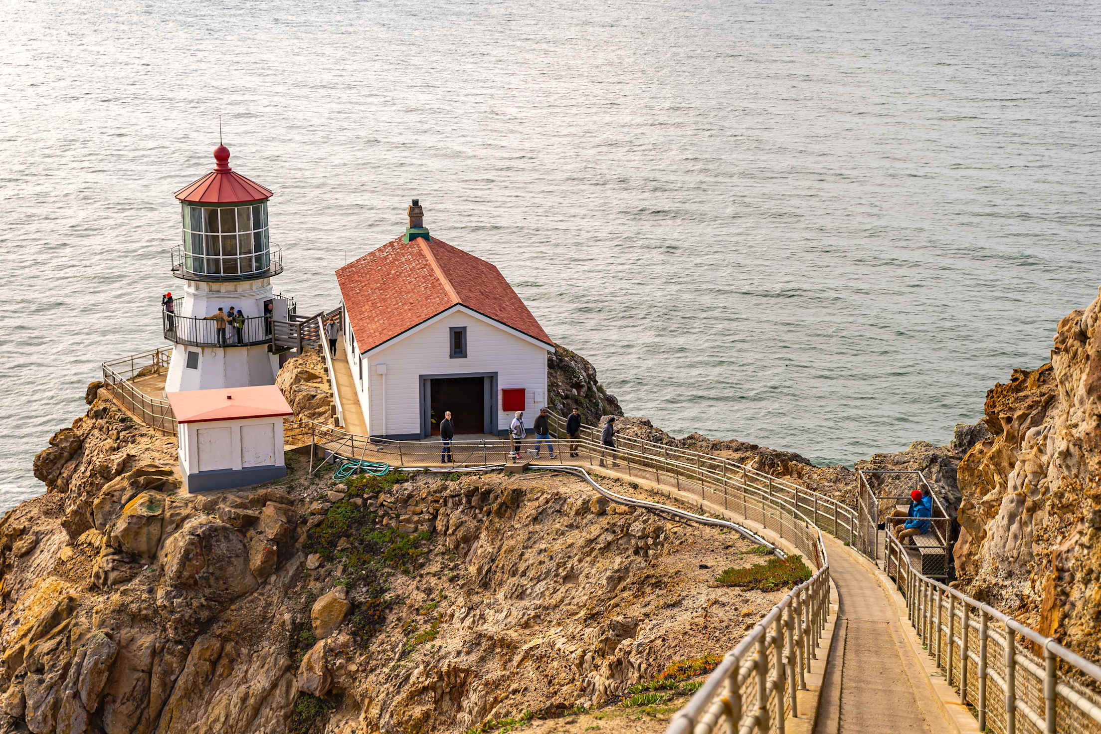 people walk the stairs to the Point Reyes Lighthouse with the ocean in the background