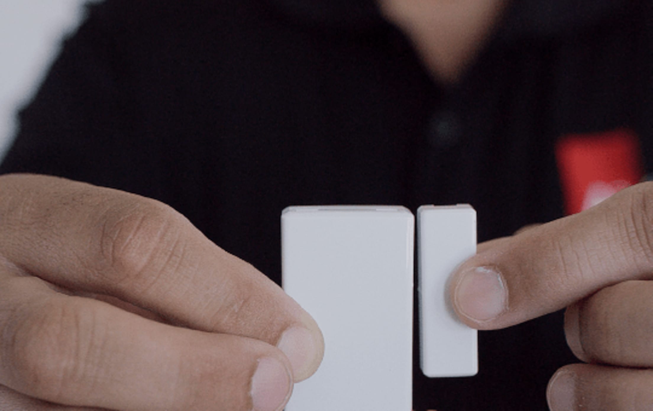 A person holding the magnet and contact no more than a ½-inch apart