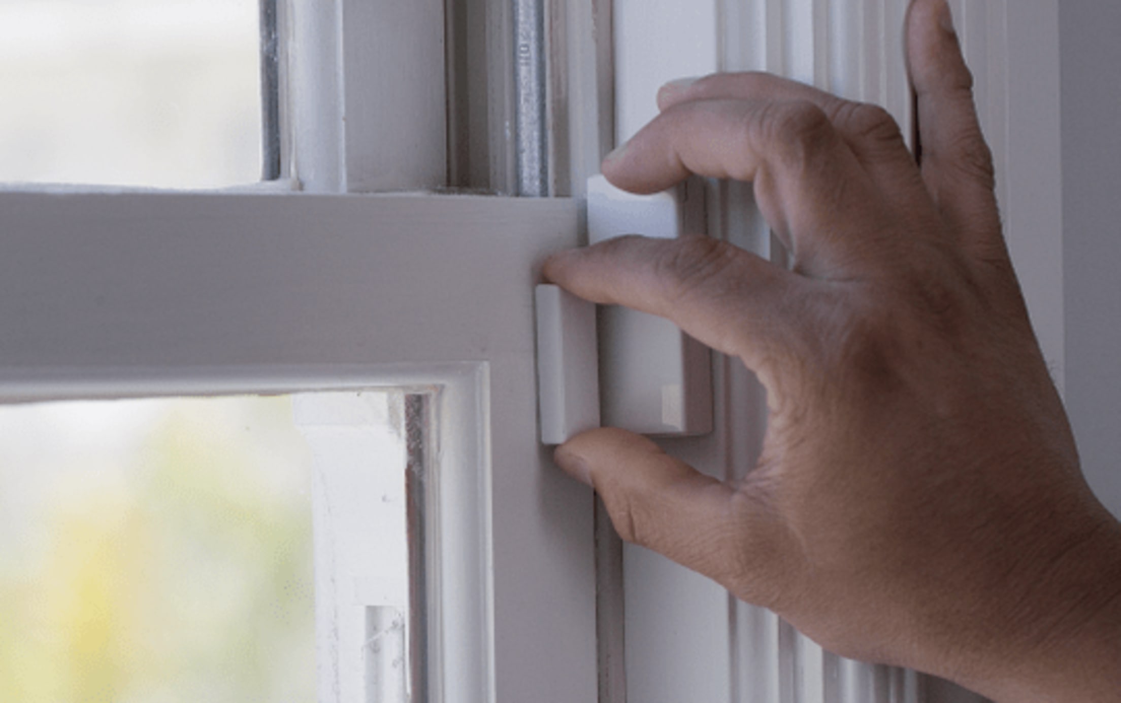 A hand placing the magnet on the window