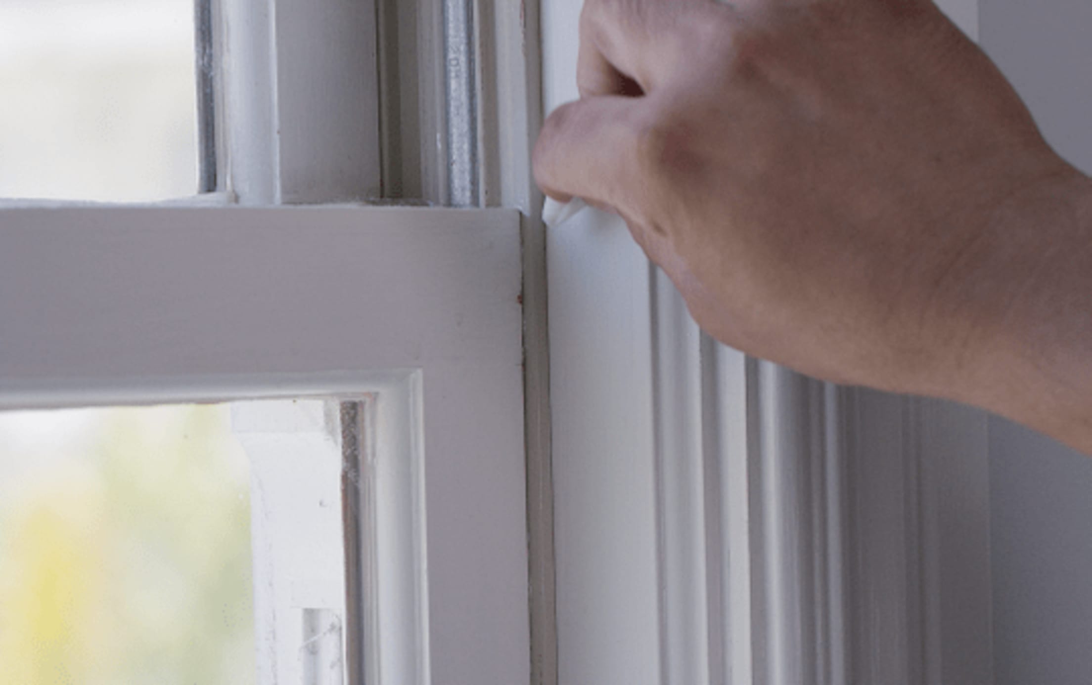 A hand wiping down the area to be attached with an entry sensor
