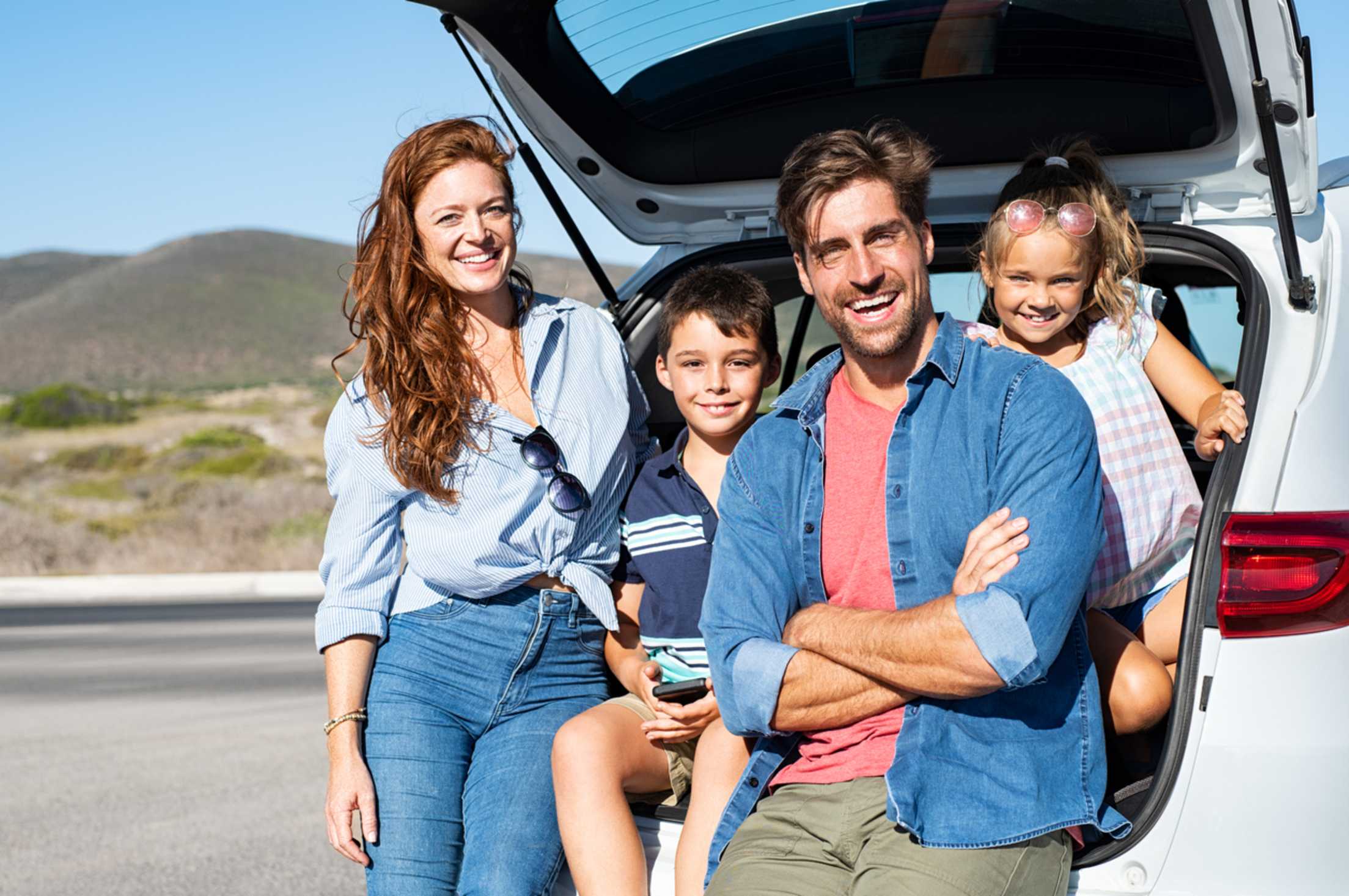 A family sits on their open hatchback.