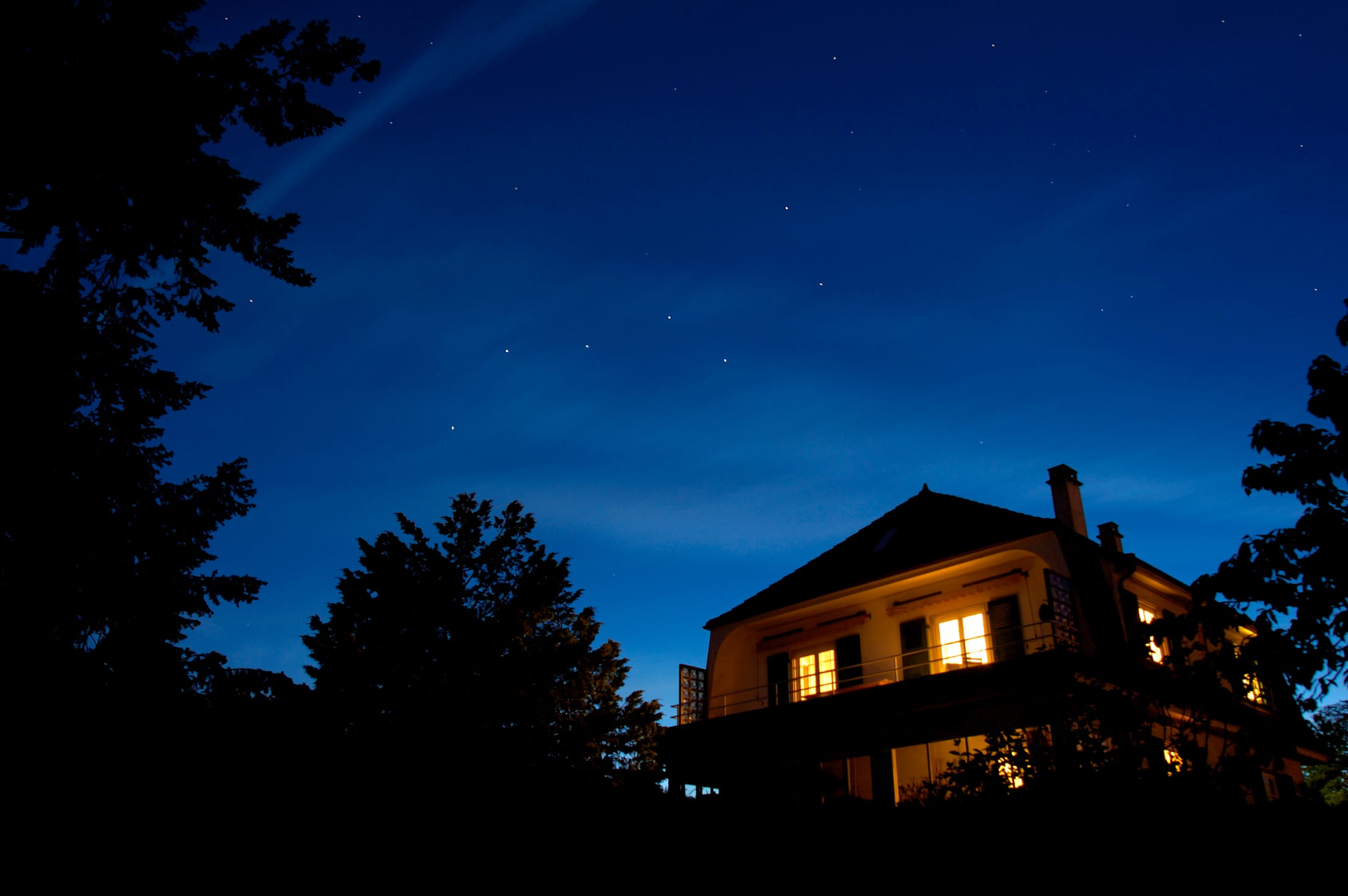 Stars come out over a home lit up at night.