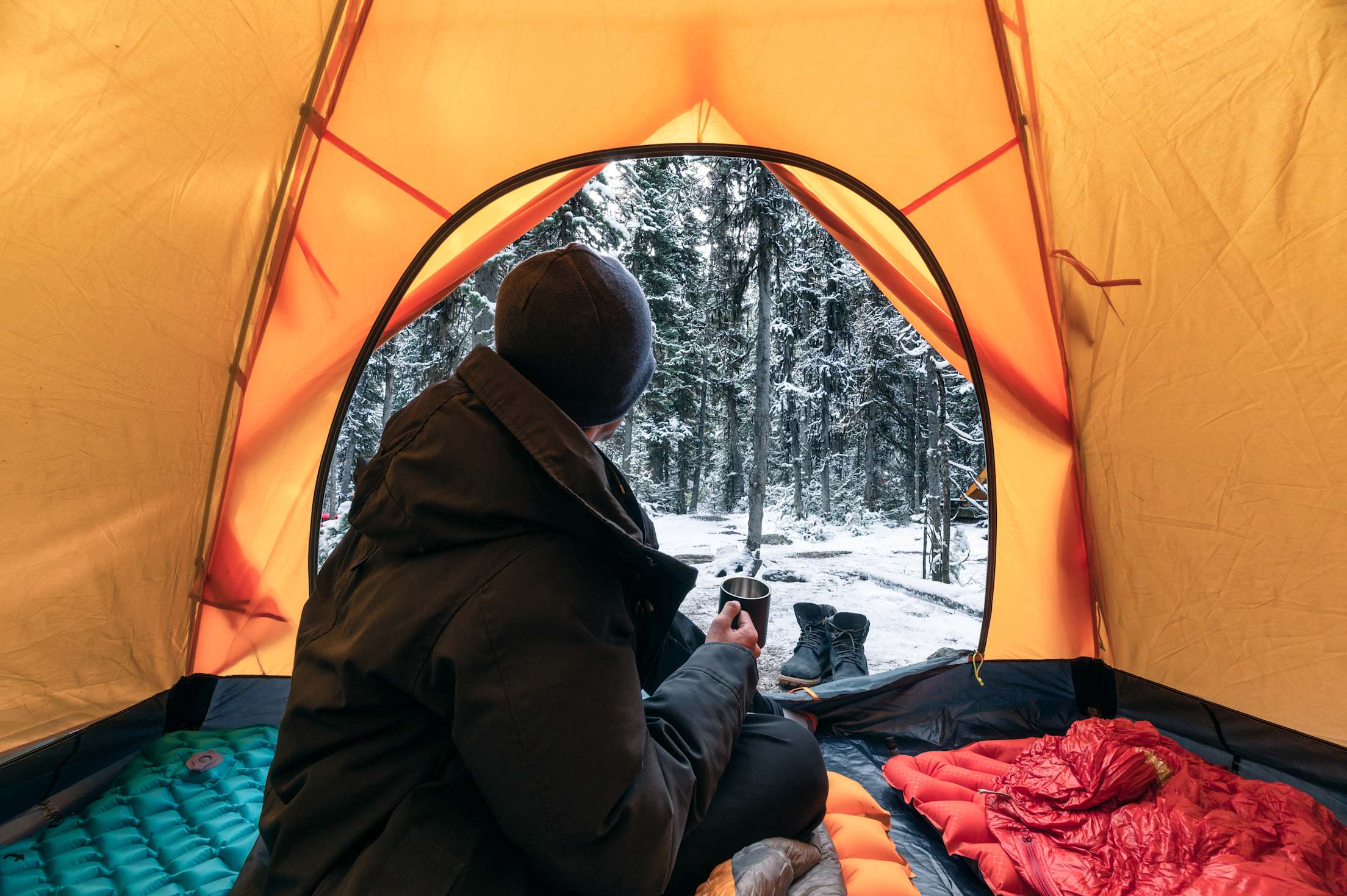 A camper drinks a cup of tea inside their tent.