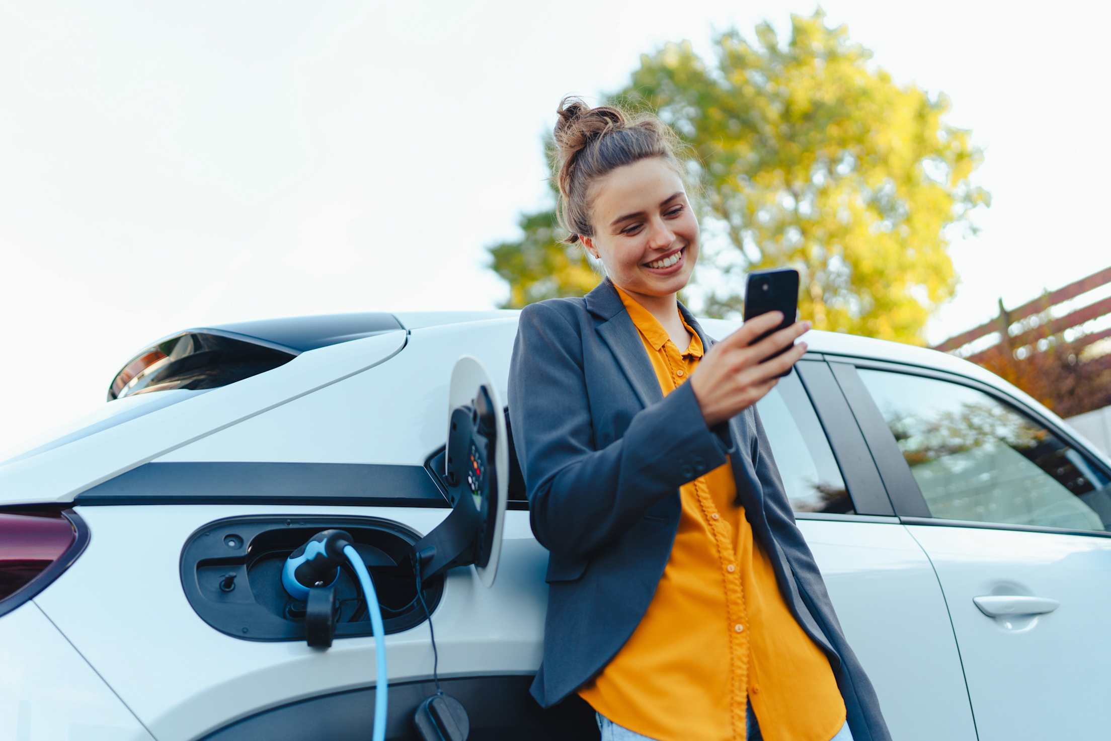 Woman standing next to her EV while it is charging