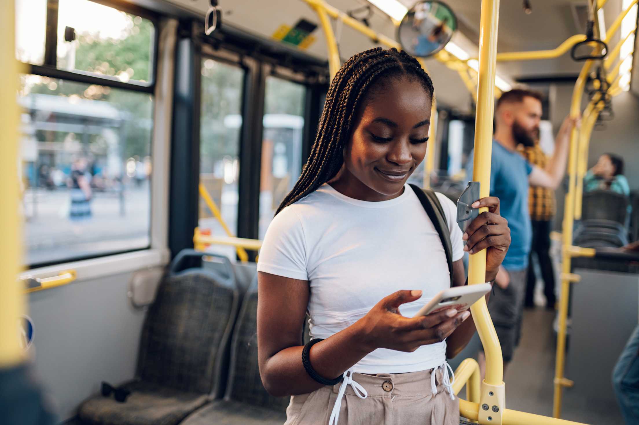A woman uses her phone while she rides a light rail train.