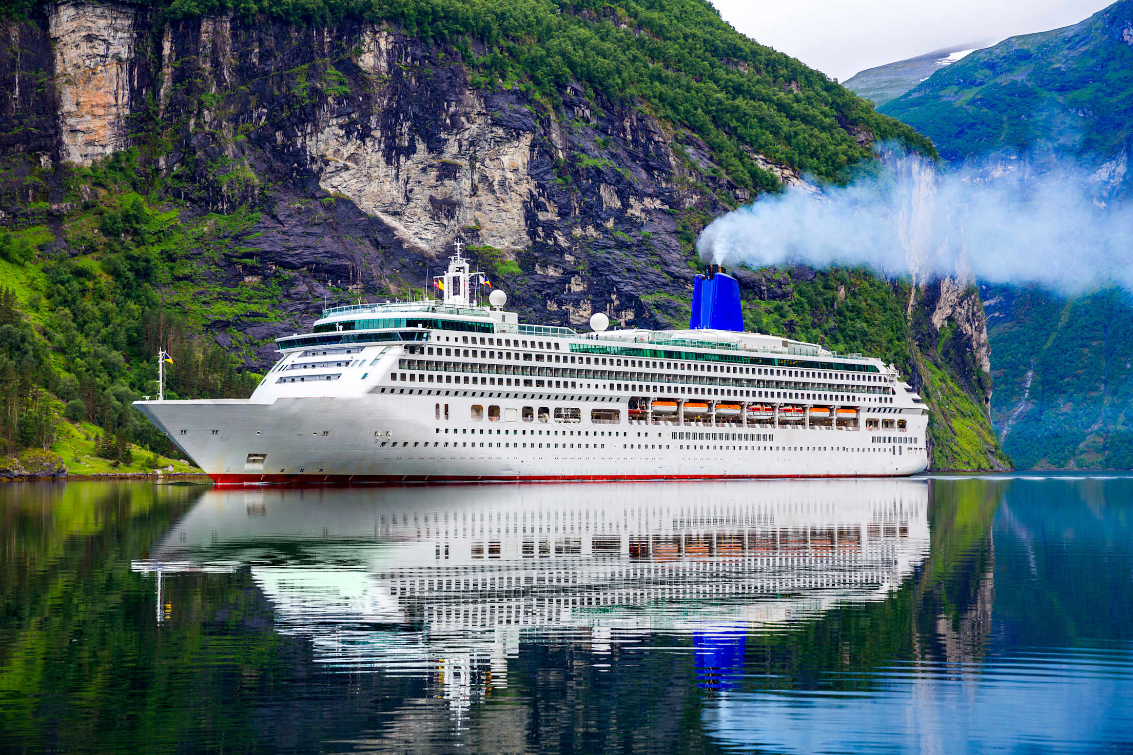 A large cruise ship sails into Geiranger Fjord, Norway.