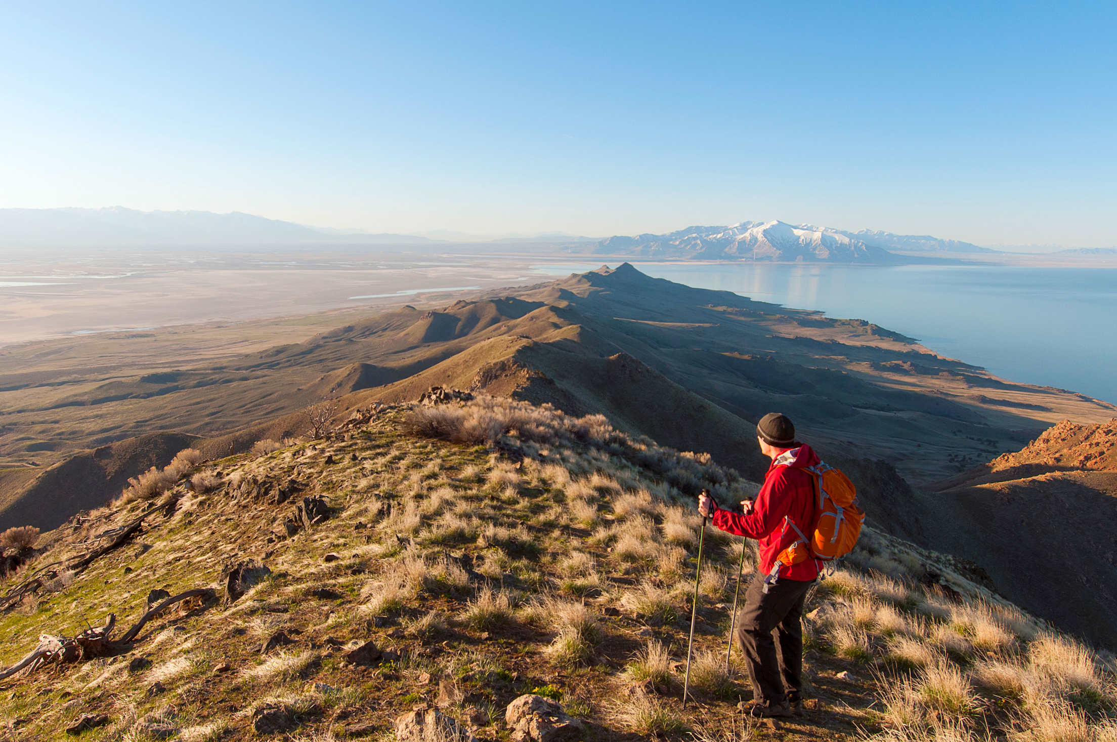 A male hiker stands on top of Frary Peak on Antelope Island, overlooking the Great Salt Lake.