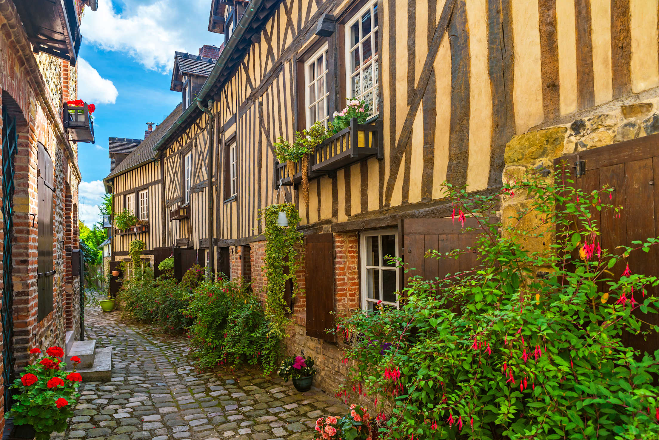 An alleyway lined with historic half-timbered buildings in Honfleur, France.