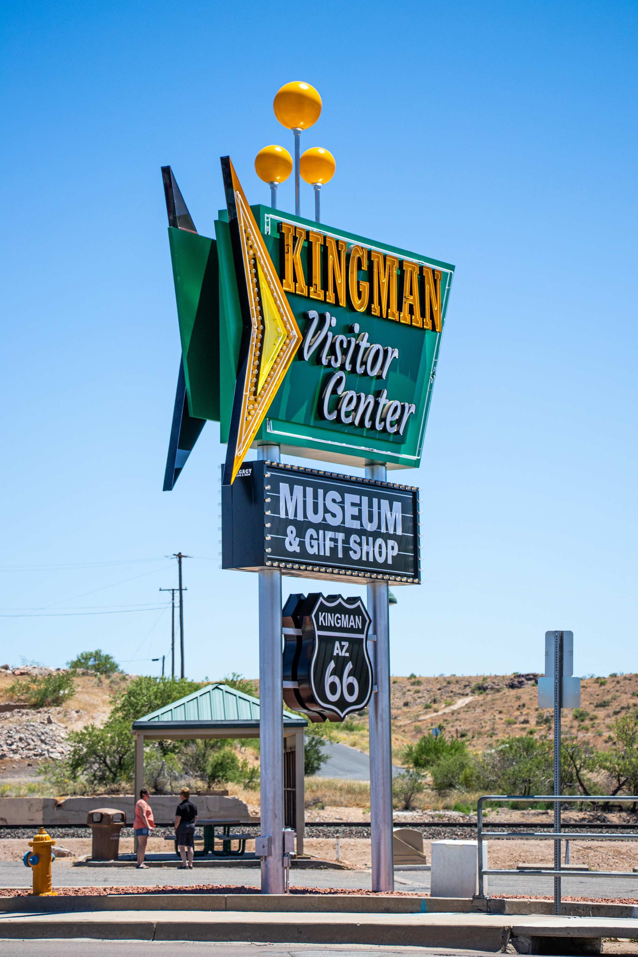 Yellow and green Kingman Visitor Center sign on Andy Devine/Route 66 in Kingman, Arizona on a clear day.