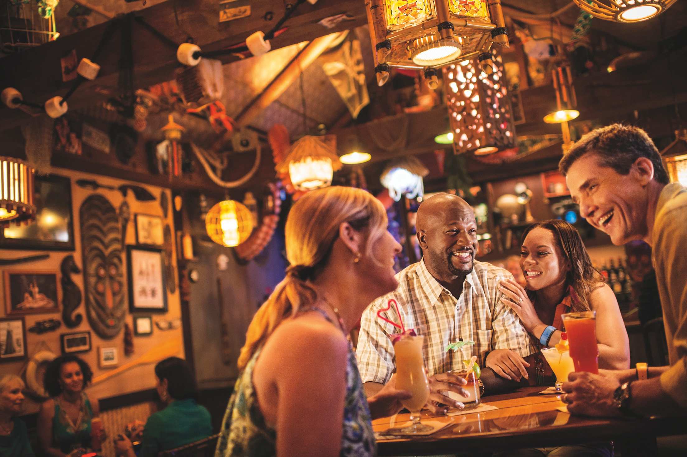 Friends chat over drinks inside Trader Sam's Enchanted Tiki Bar.