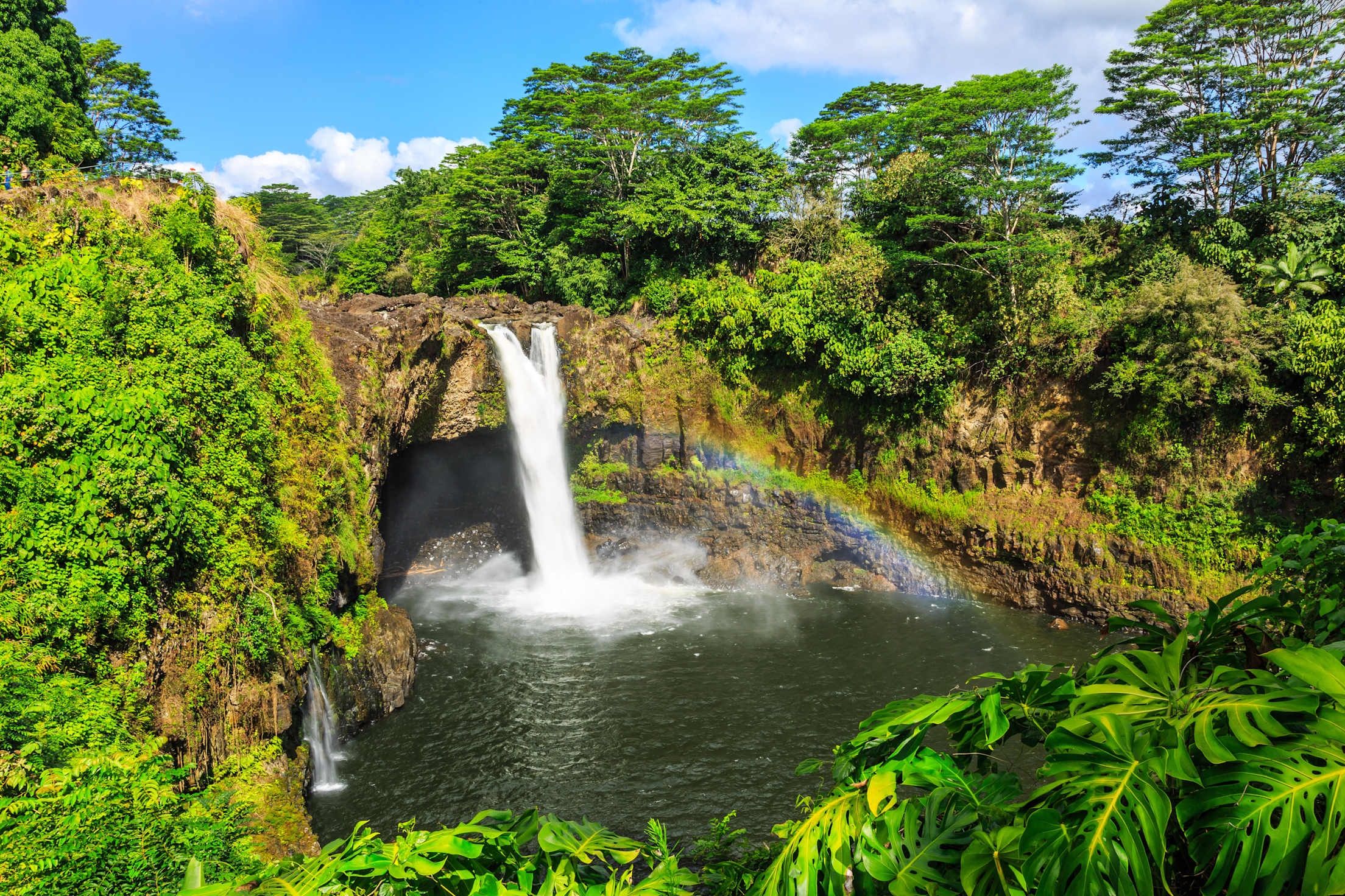 A rainbow shines under Rainbow Falls in Hilo, Hawaii.