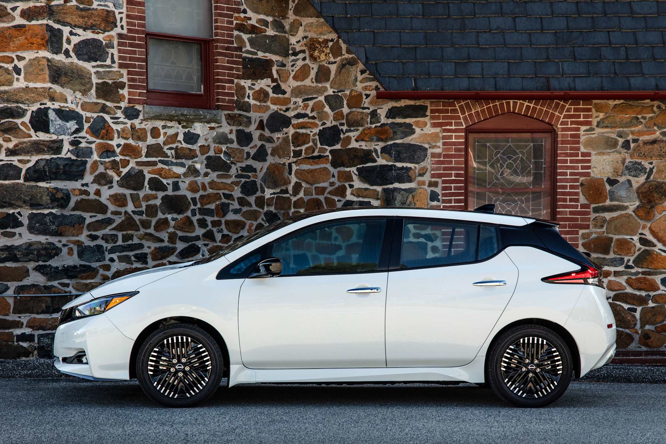 2025 Nissan Leaf parked in front of a stone home.