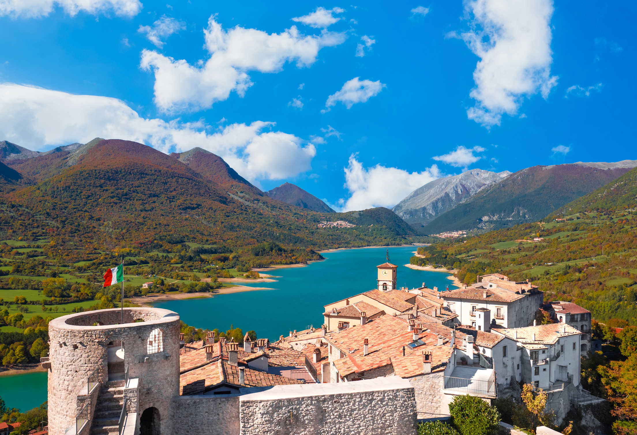 Stone buildings overlook Barrea Lake and Lazio and Molise National Park in Italy.