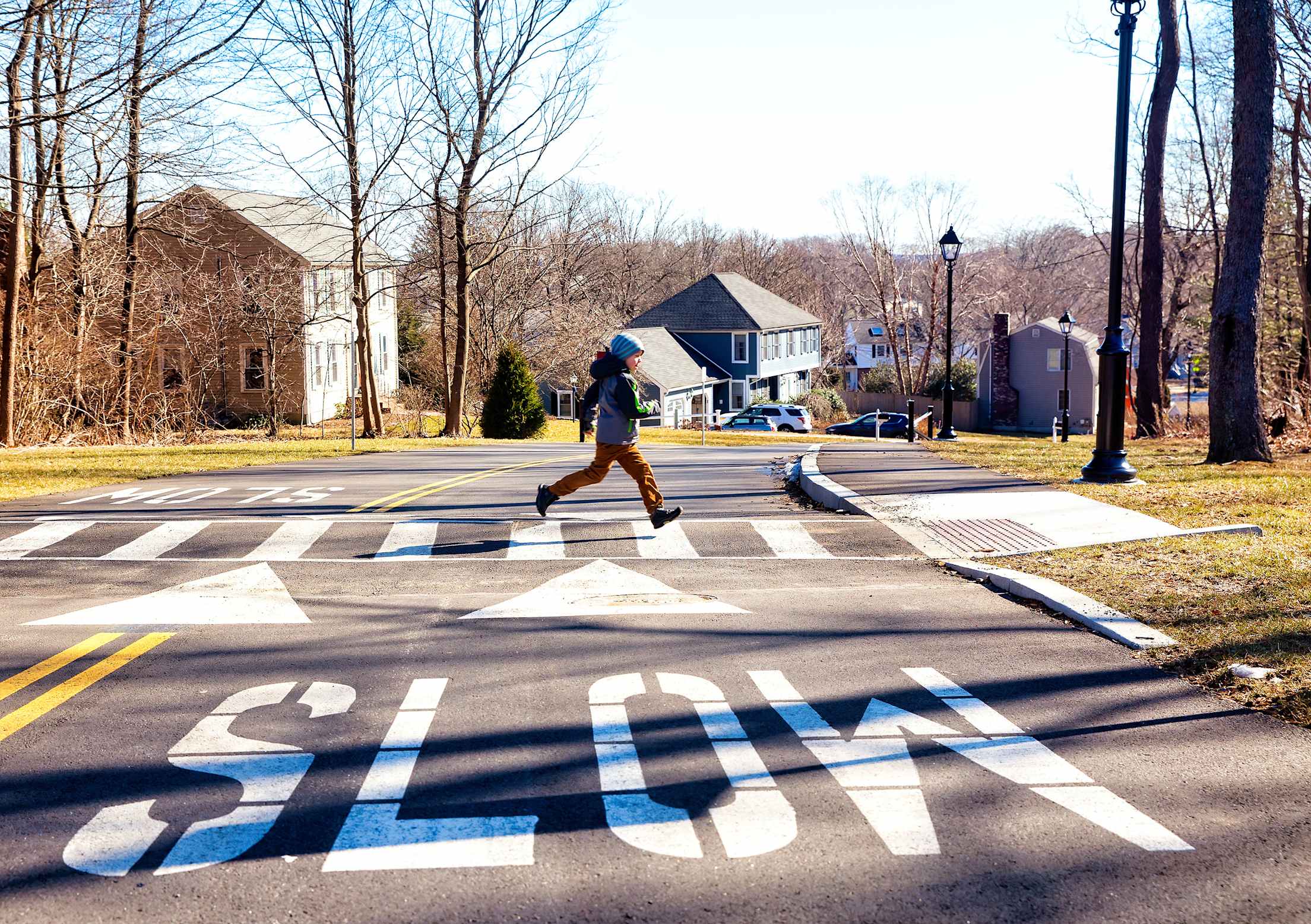 A child runs across a crosswalk in fall.
