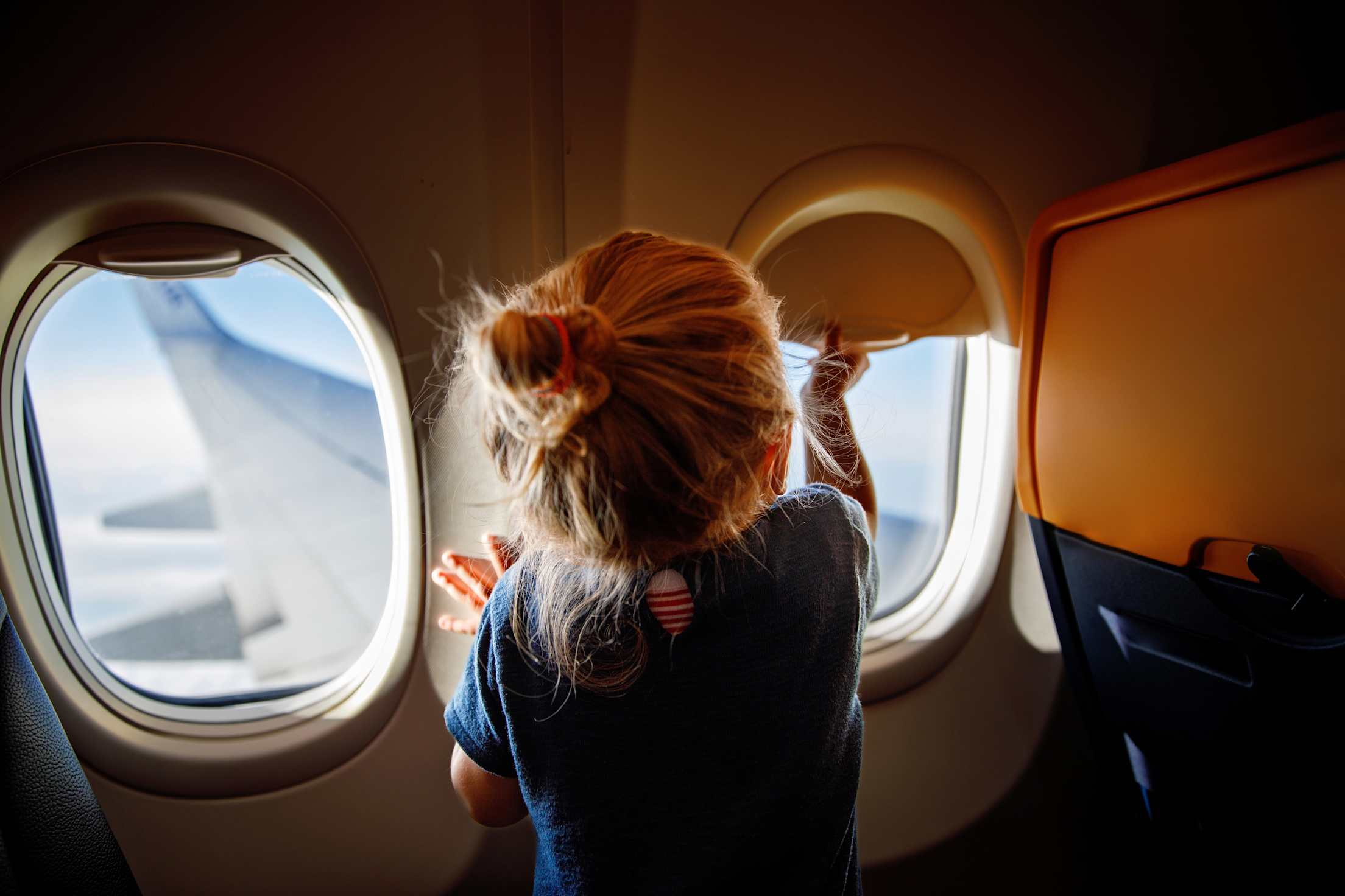 A young girl looks out the window on an airplane.