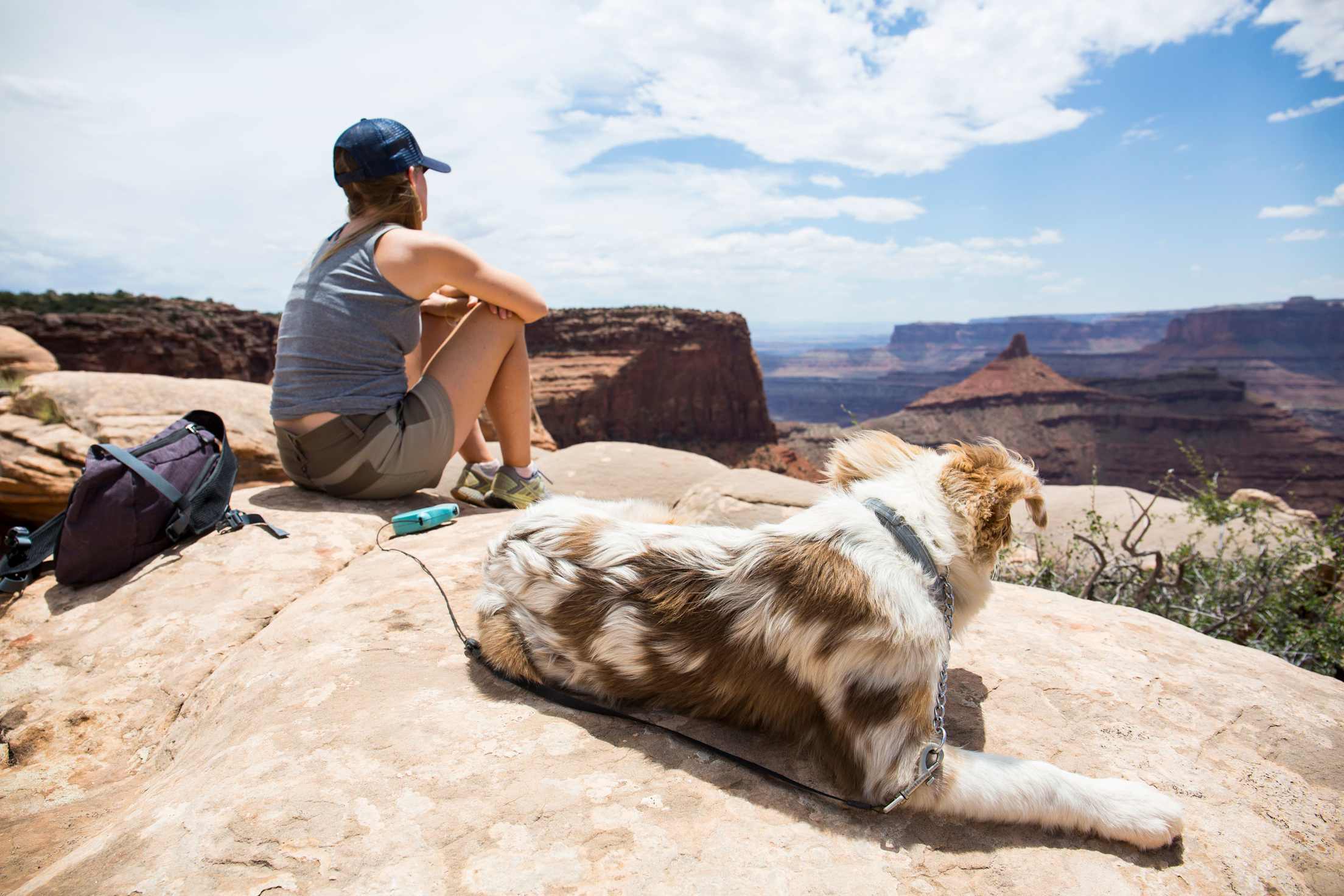 A hiker sits with her Australian Shepherd puppy in Utah's dog-friendly Dead Horse Point State Park.