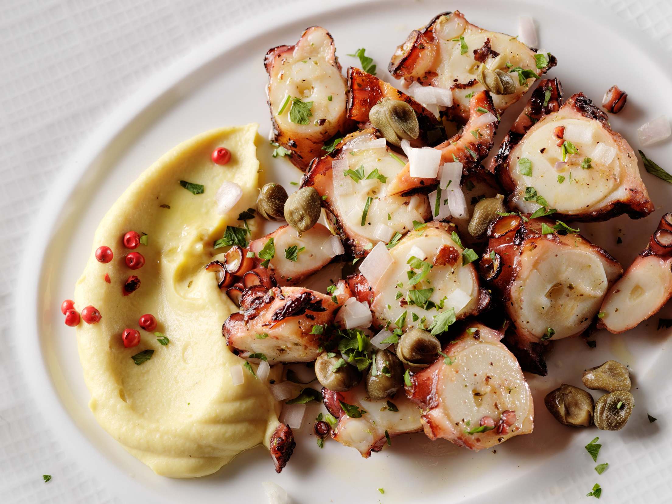 Estiatorio Milos's char-grilled octopus on a white plate.