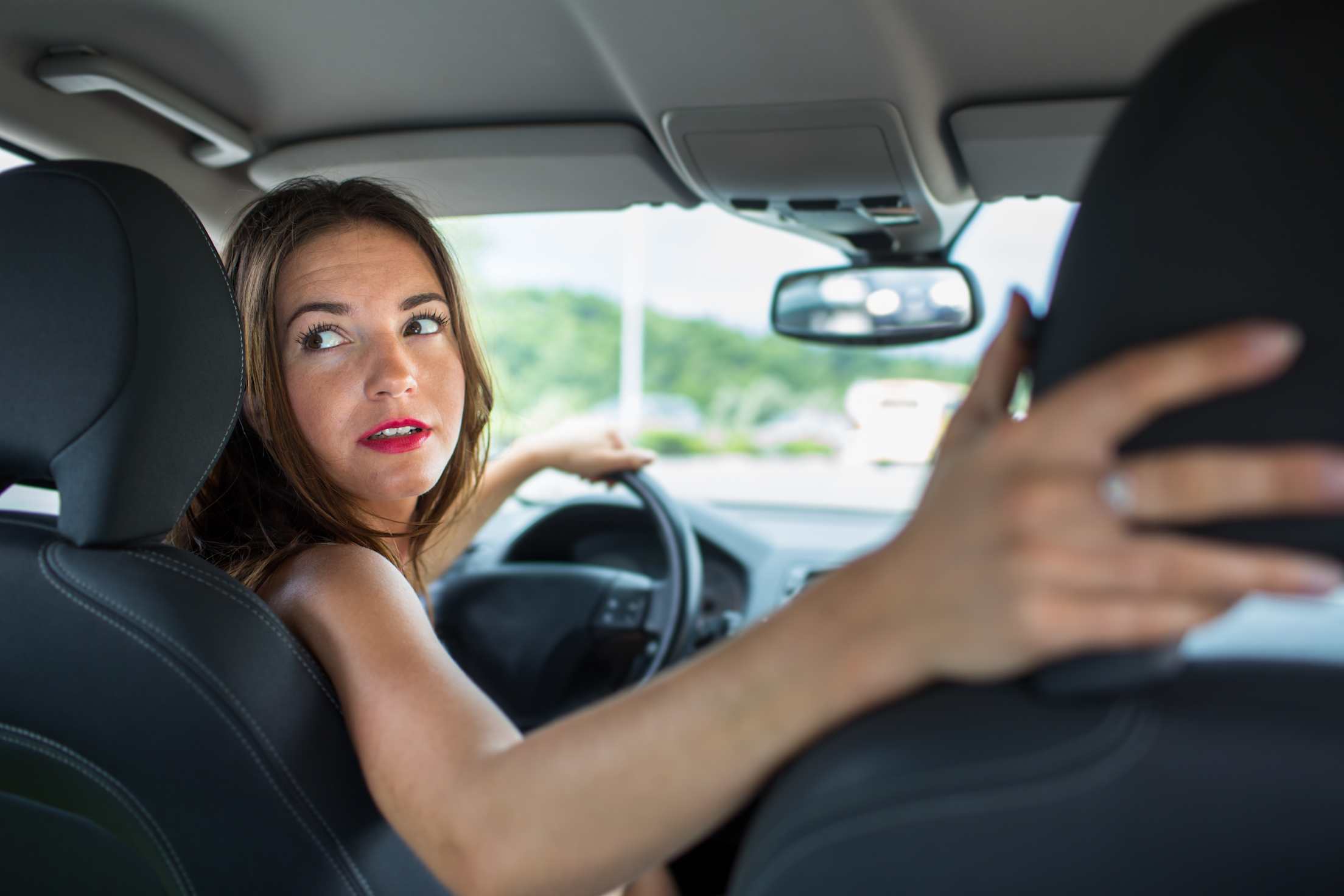 A female driver looks over her right shoulder.