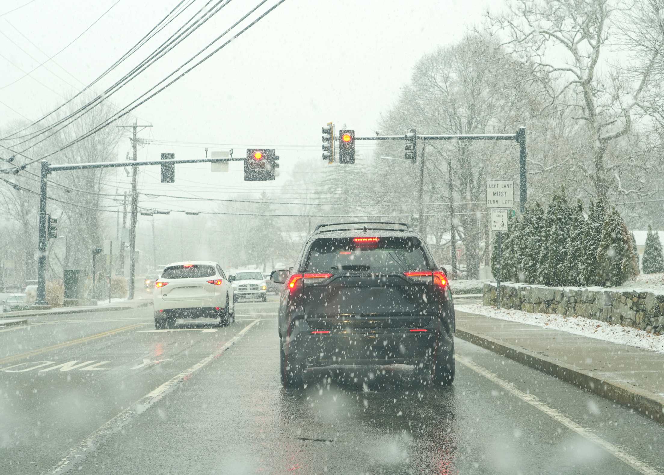 Cars stopped at a traffic light in snowy weather.