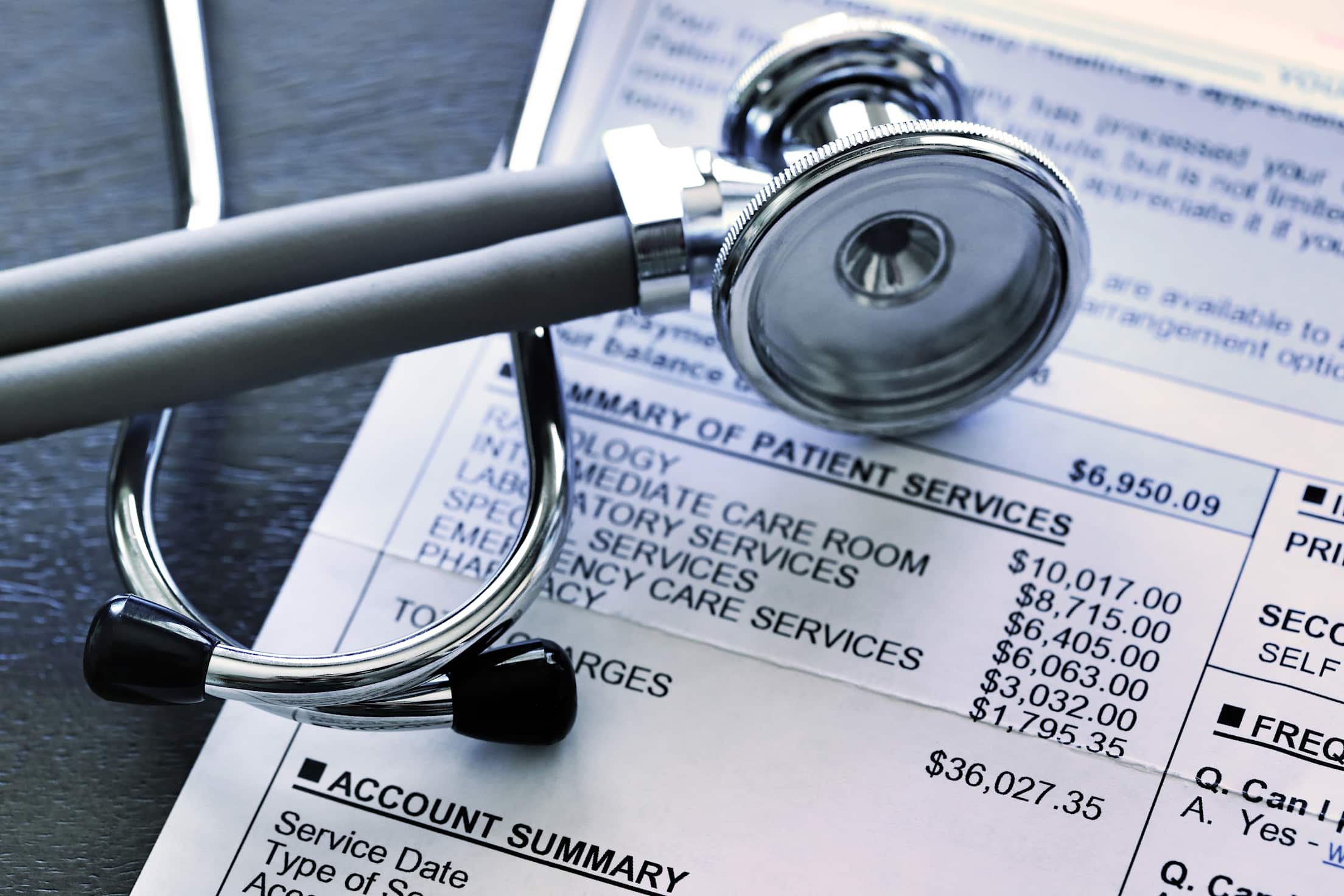 a stethoscope is seen resting on a medical bill with charges totalling $36,02735