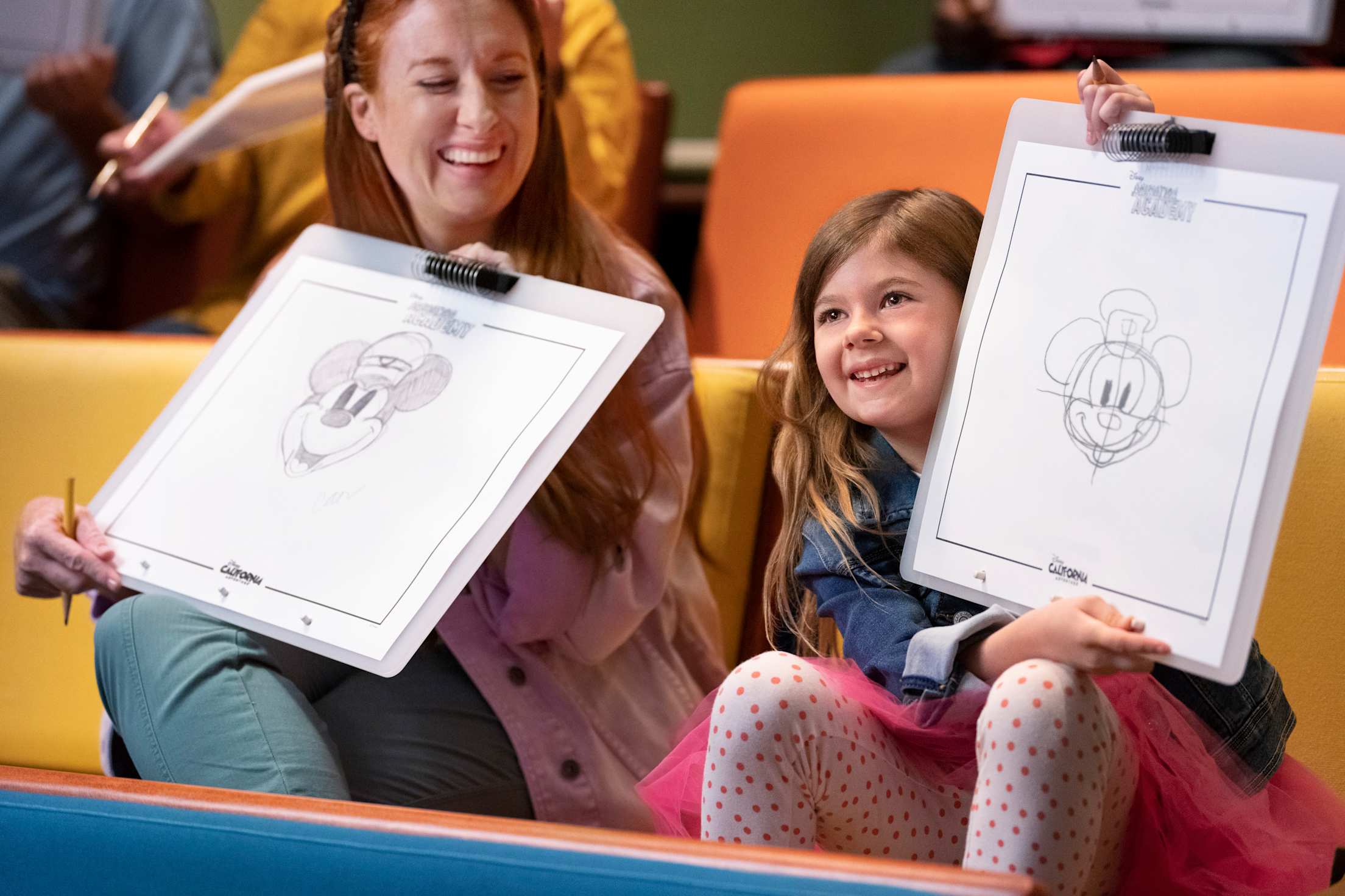 A mother and daughter hold up the sketches they made at Disneyland's Animation Academy.