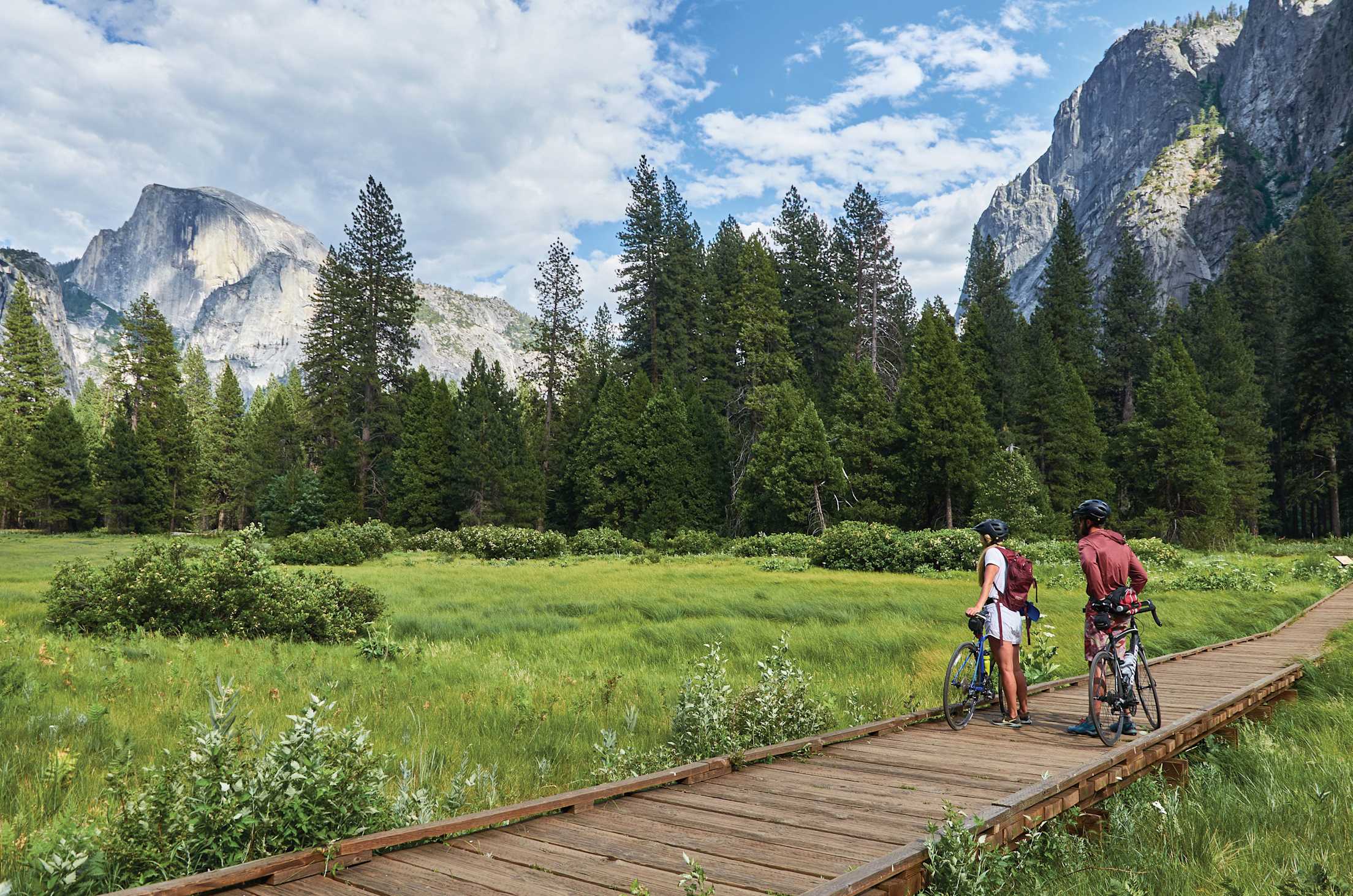 Two bicyclists stop to gaze at Half Dome from the Yosemite valley floor.