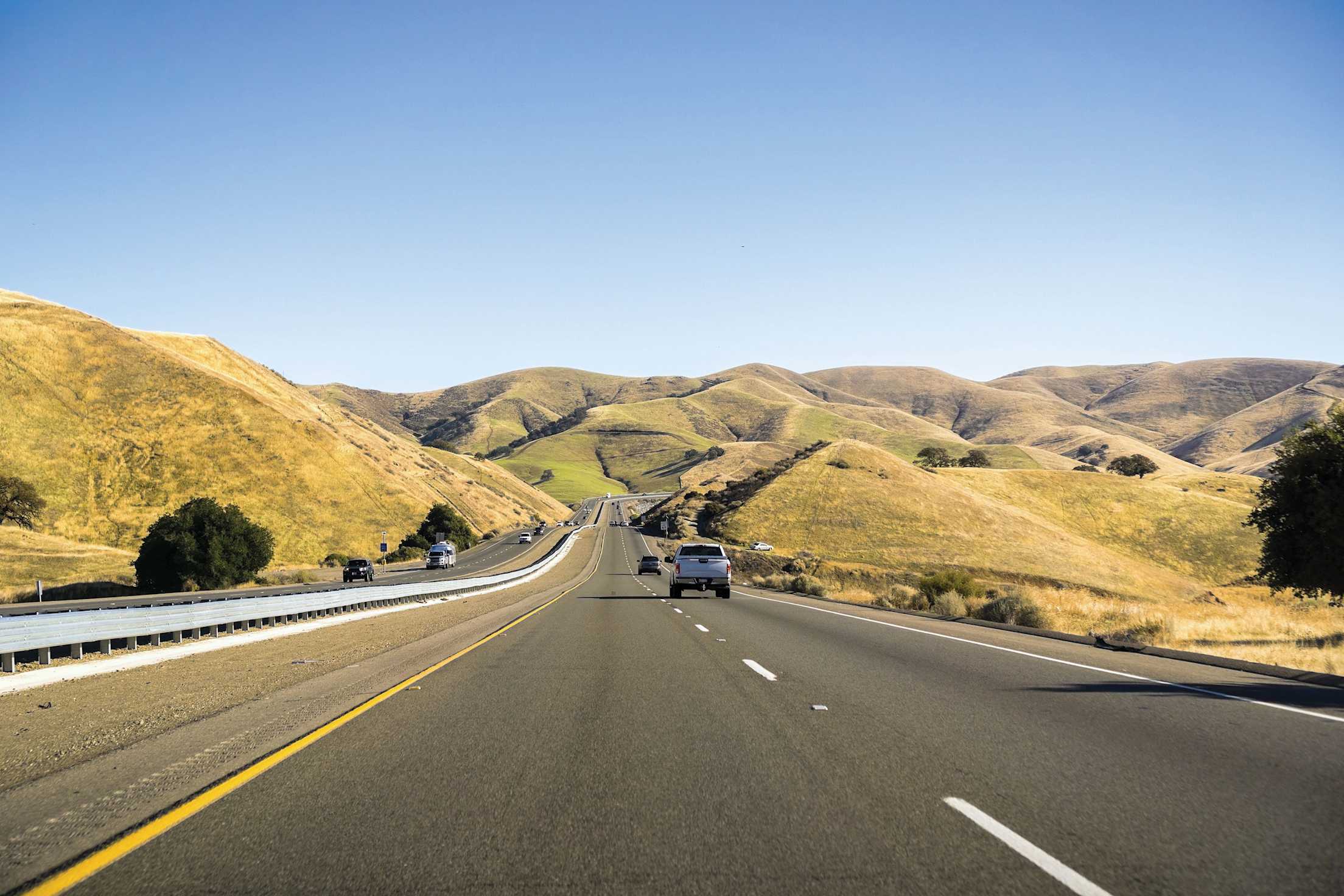 A divided highway cuts through the rolling hills of San Luis Obispo, California.