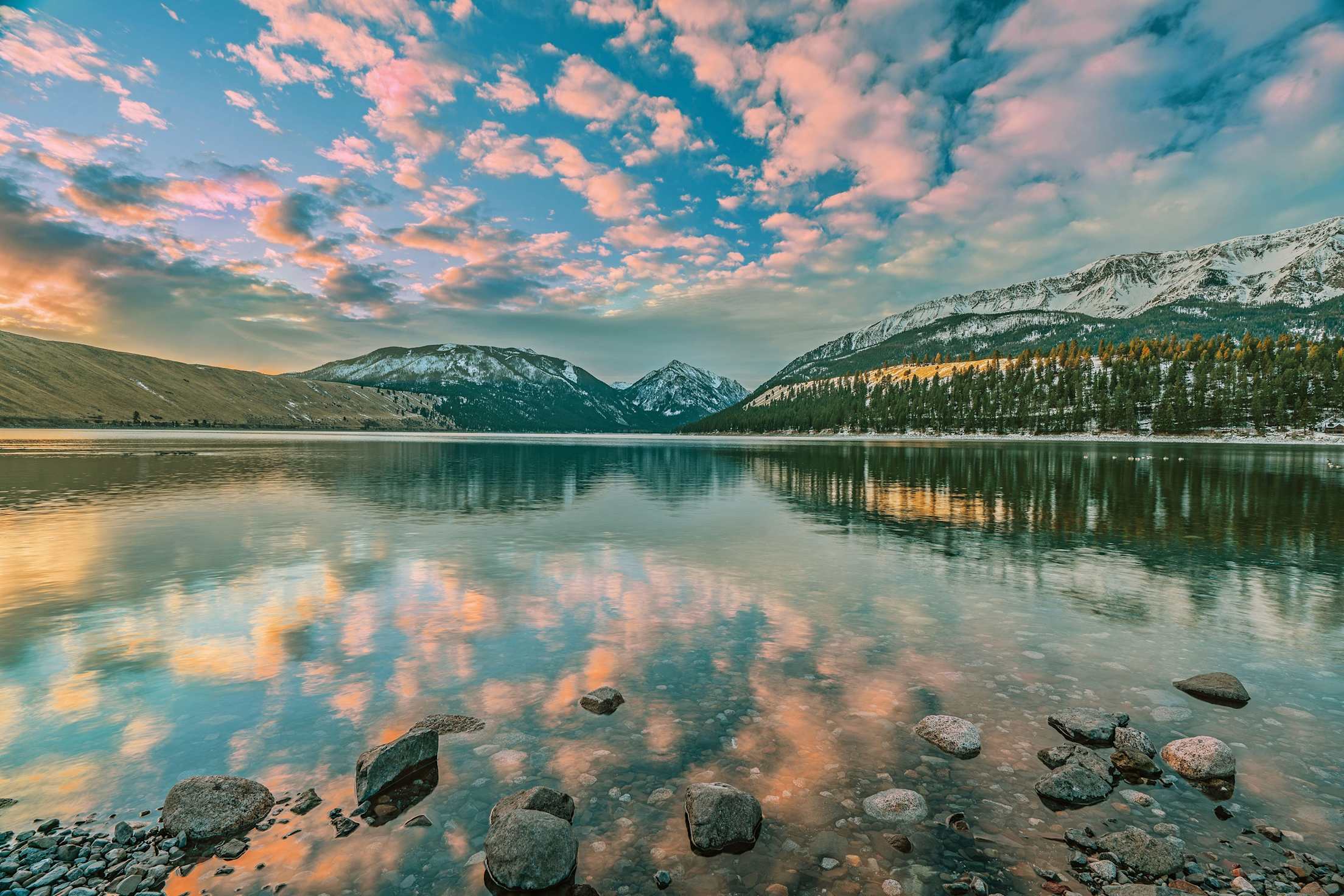 pink clouds reflected on a mountainside lake