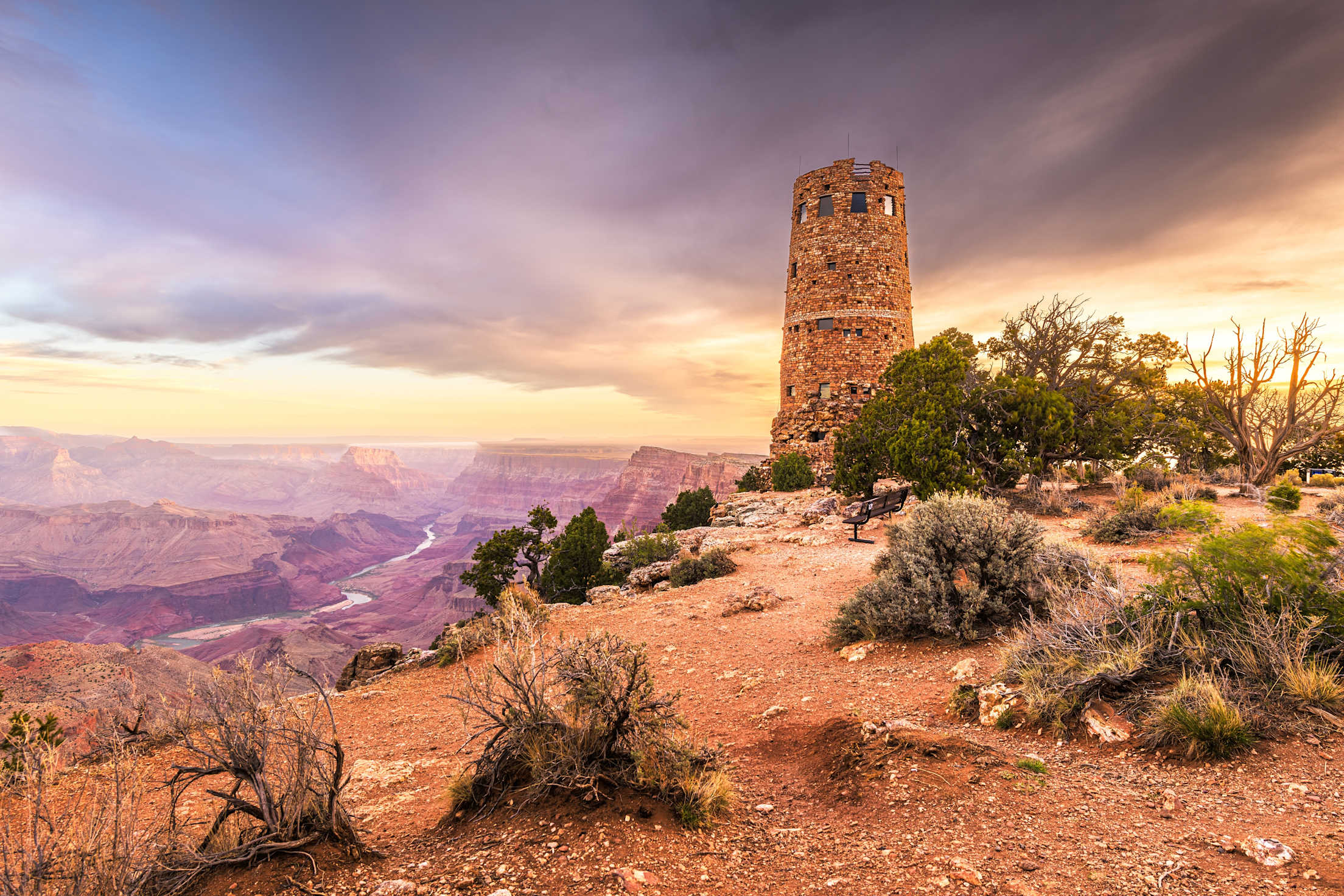 a rock watchtowner overlooking the Grand Canyon with a dramatic sunset