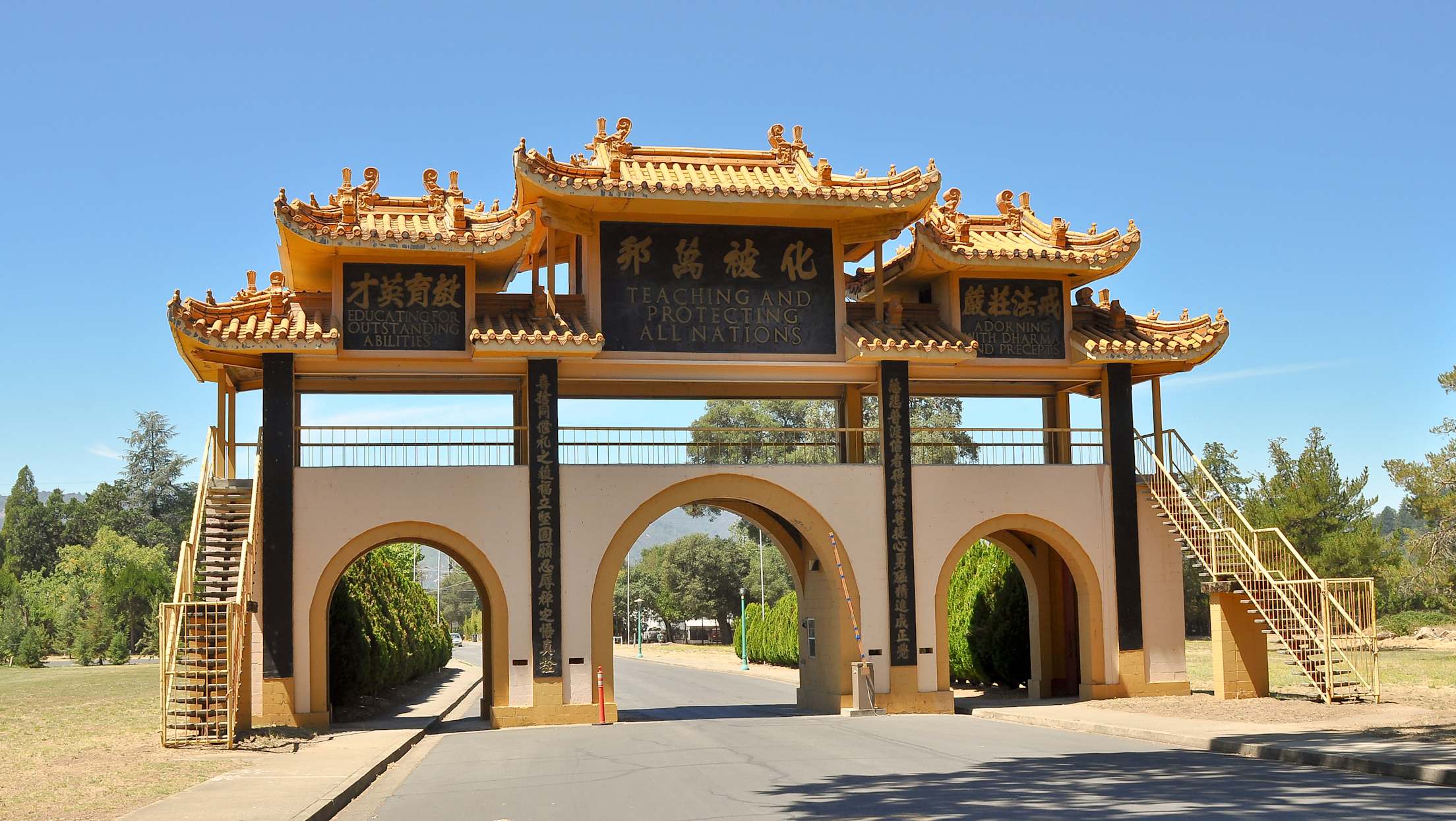 a Chinese-style entryway with a gold roof and archesGate to the City of Ten Thousand Buddhas