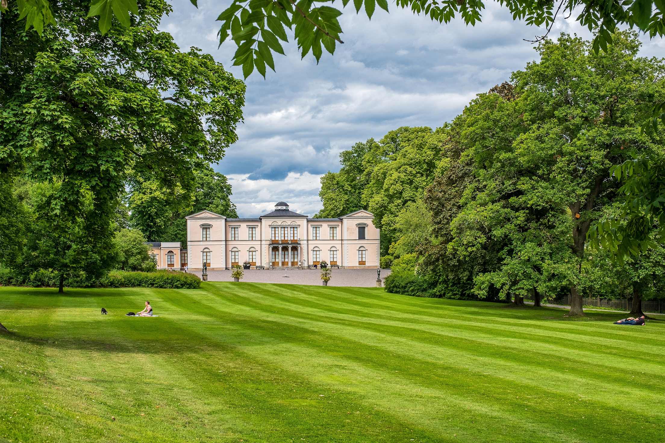 a green lawn with a grand estate in the background