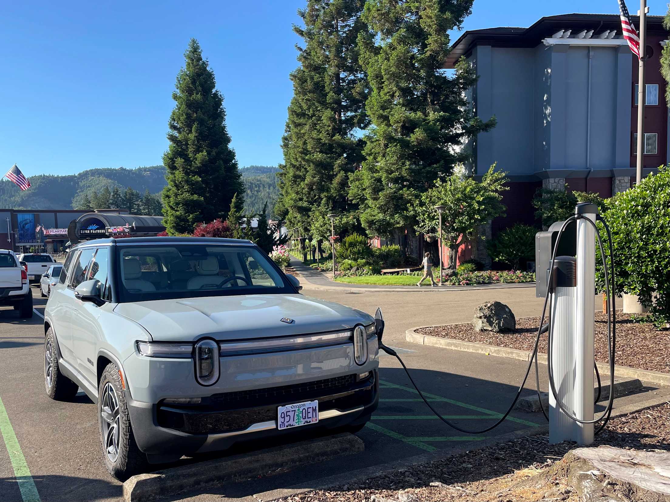 an electric vehicles charges at a station with tall trees and blue sky in the background