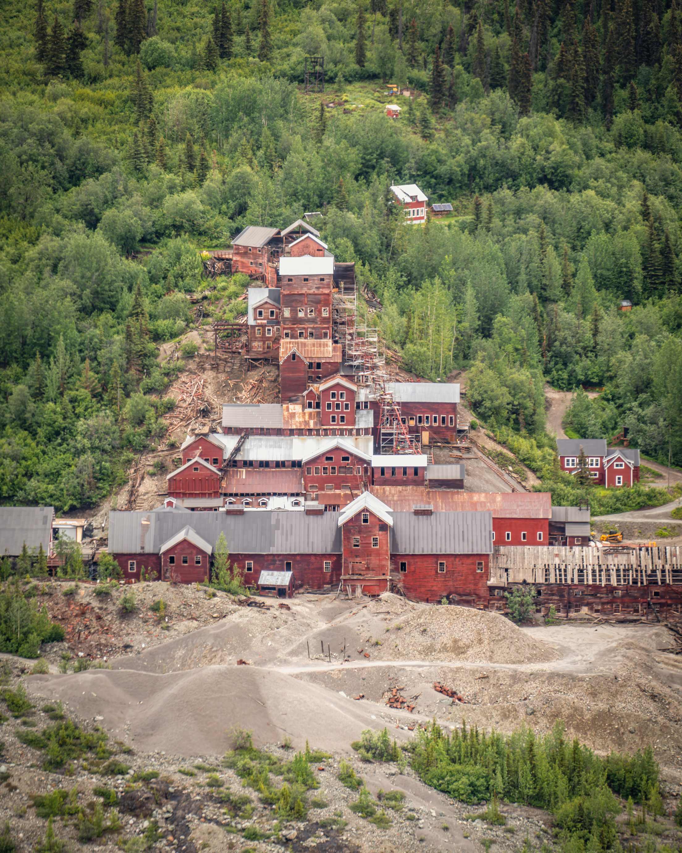 old red-tinged buildings from the 1930s on a tree-covered hill in Alaska