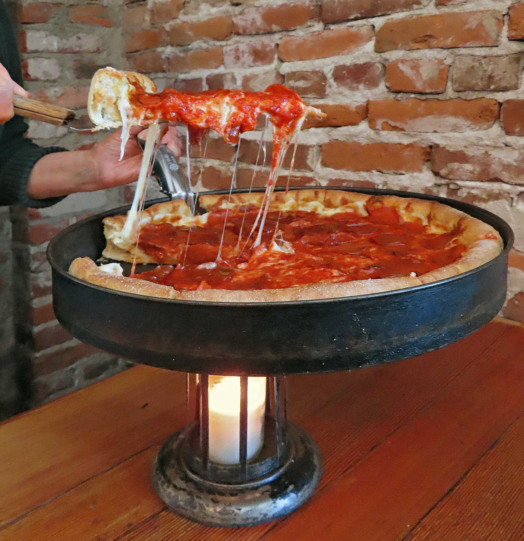 someone serves a slice of deep dish pizza