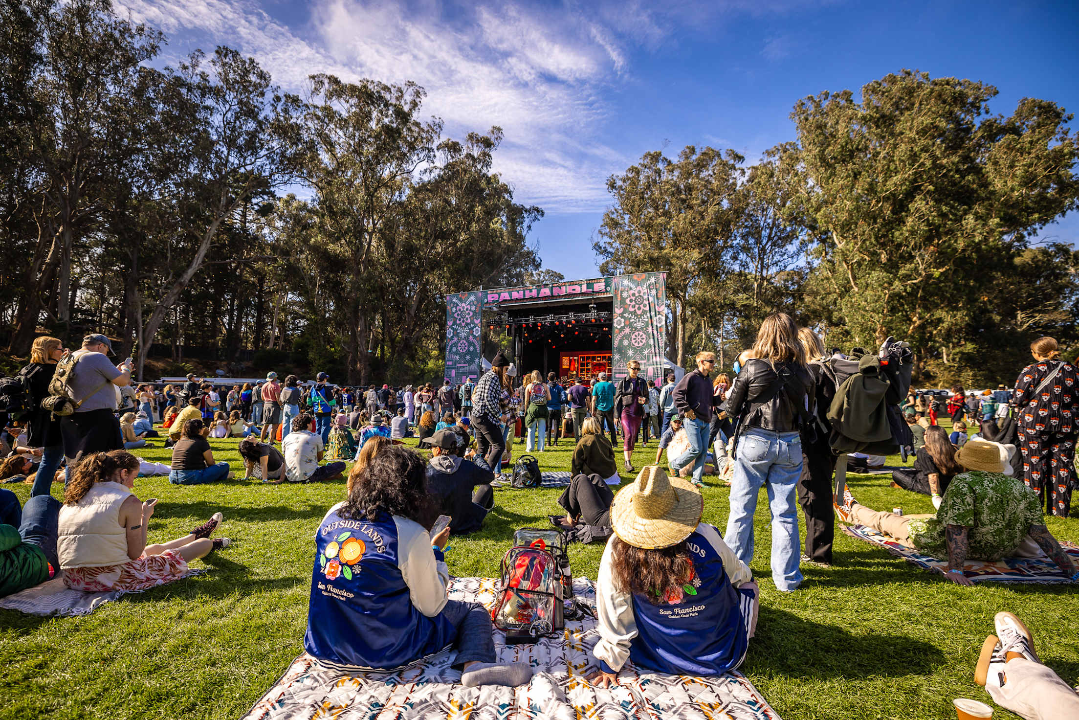 people sit on a blanket at a music festival