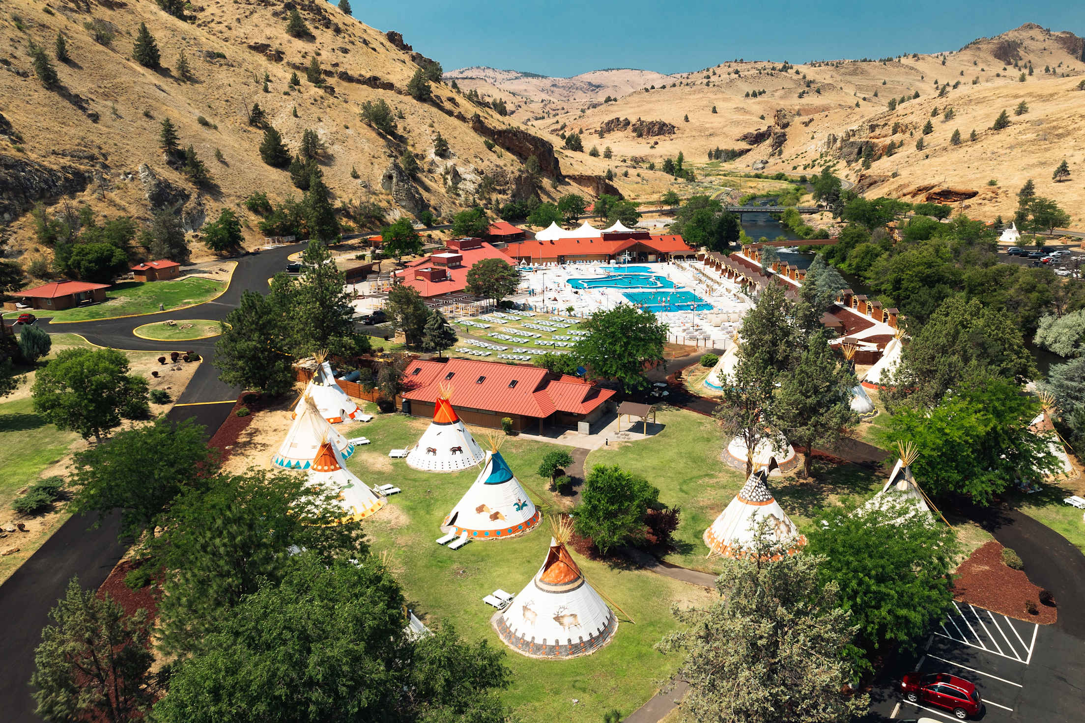 aerial view of resort with swimming pools, mountains and teepees