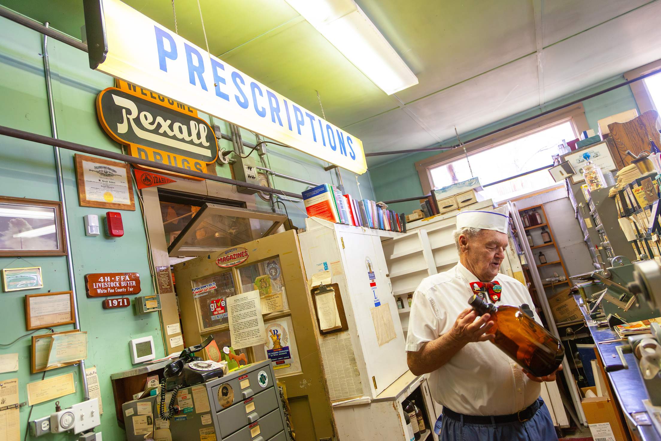 a man in an old-fashioned outfit stands in an preserved pharmacy from the 1940s