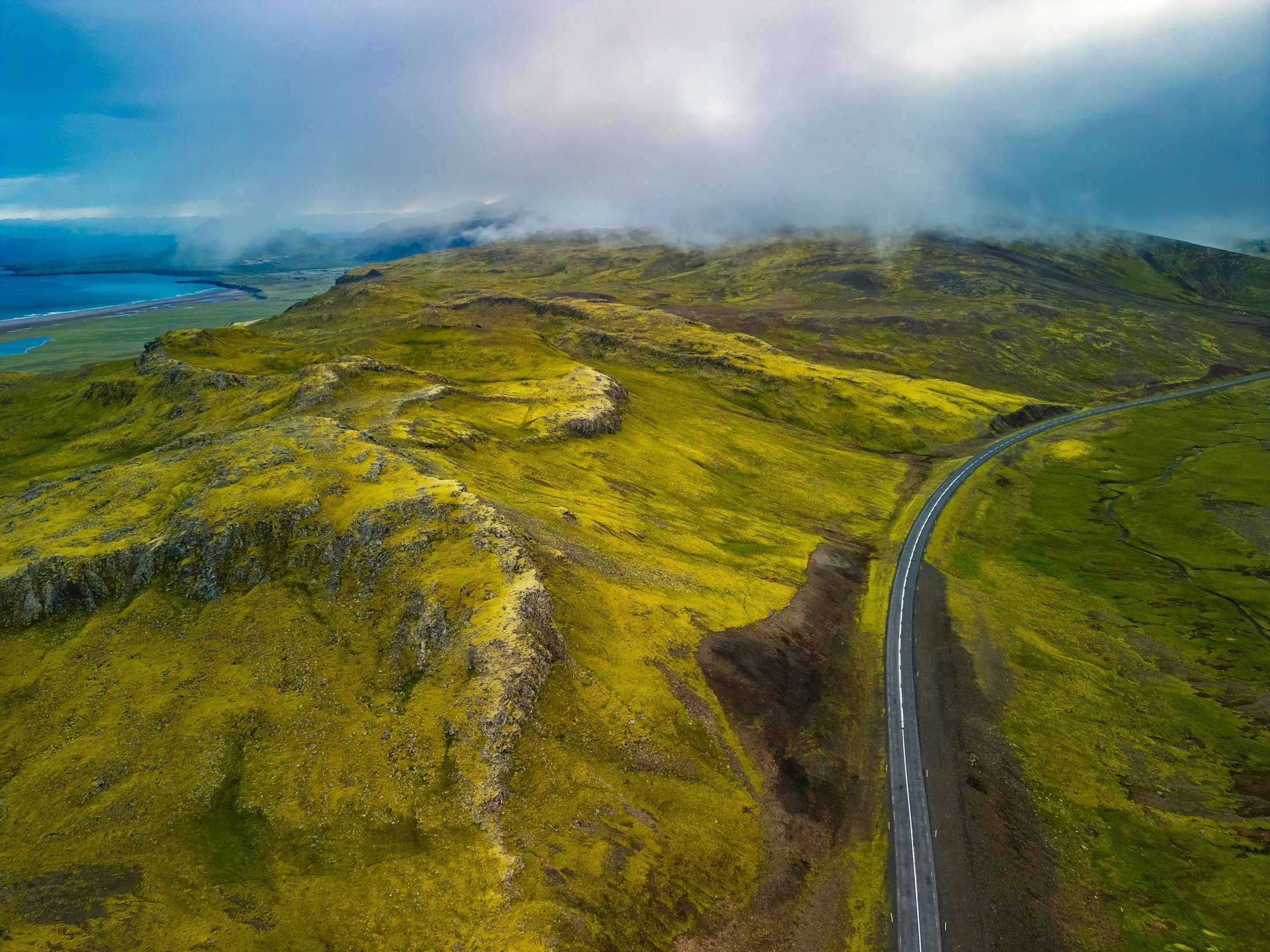 an aerial photograph of Iceland, with green rolling hills and blue sky