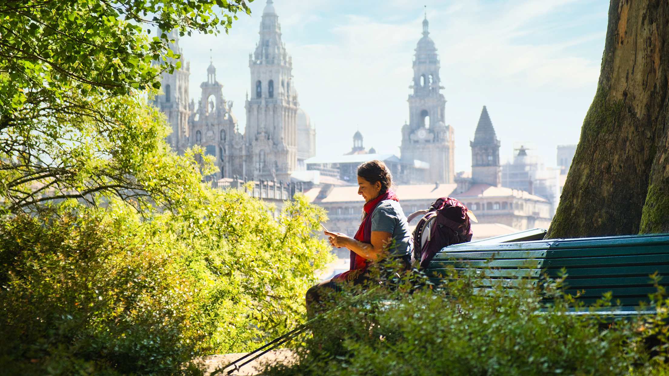 a woman pauses on a bench with a large castle in the background