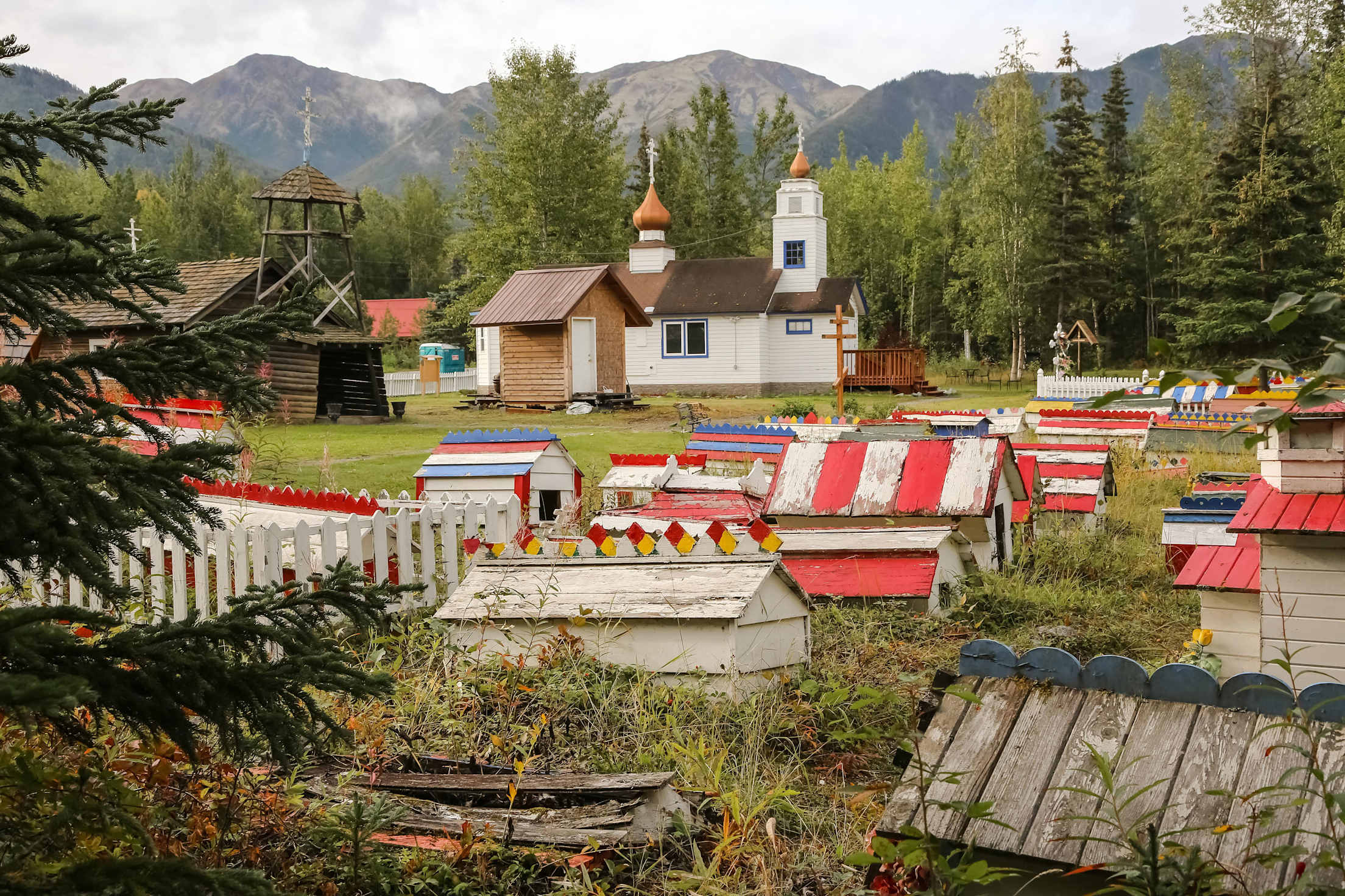 Colorful Dena'ina spirit houses beside a Russian Orthodox church