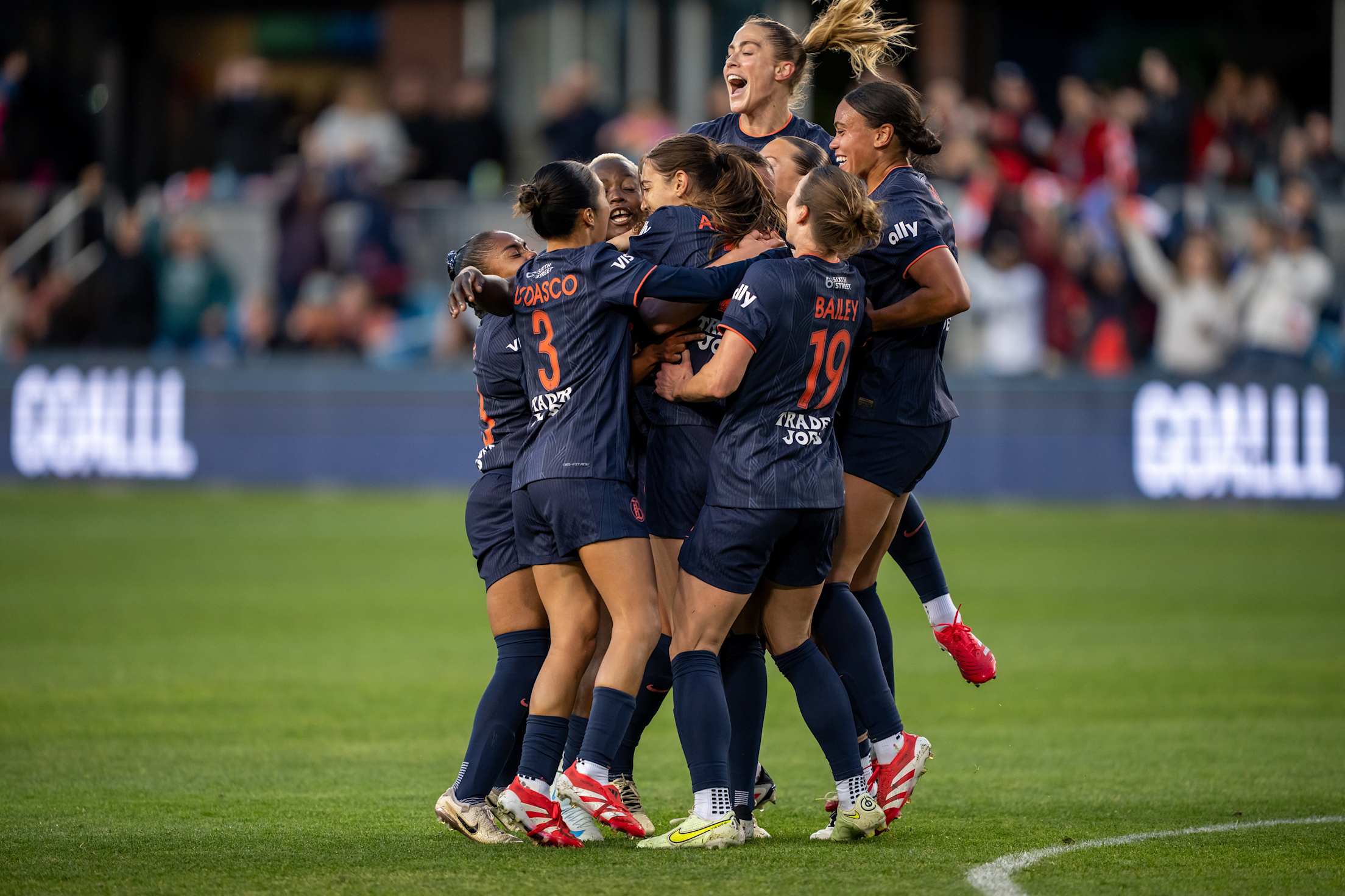 a women's soccer team jumps and celebrates on the field