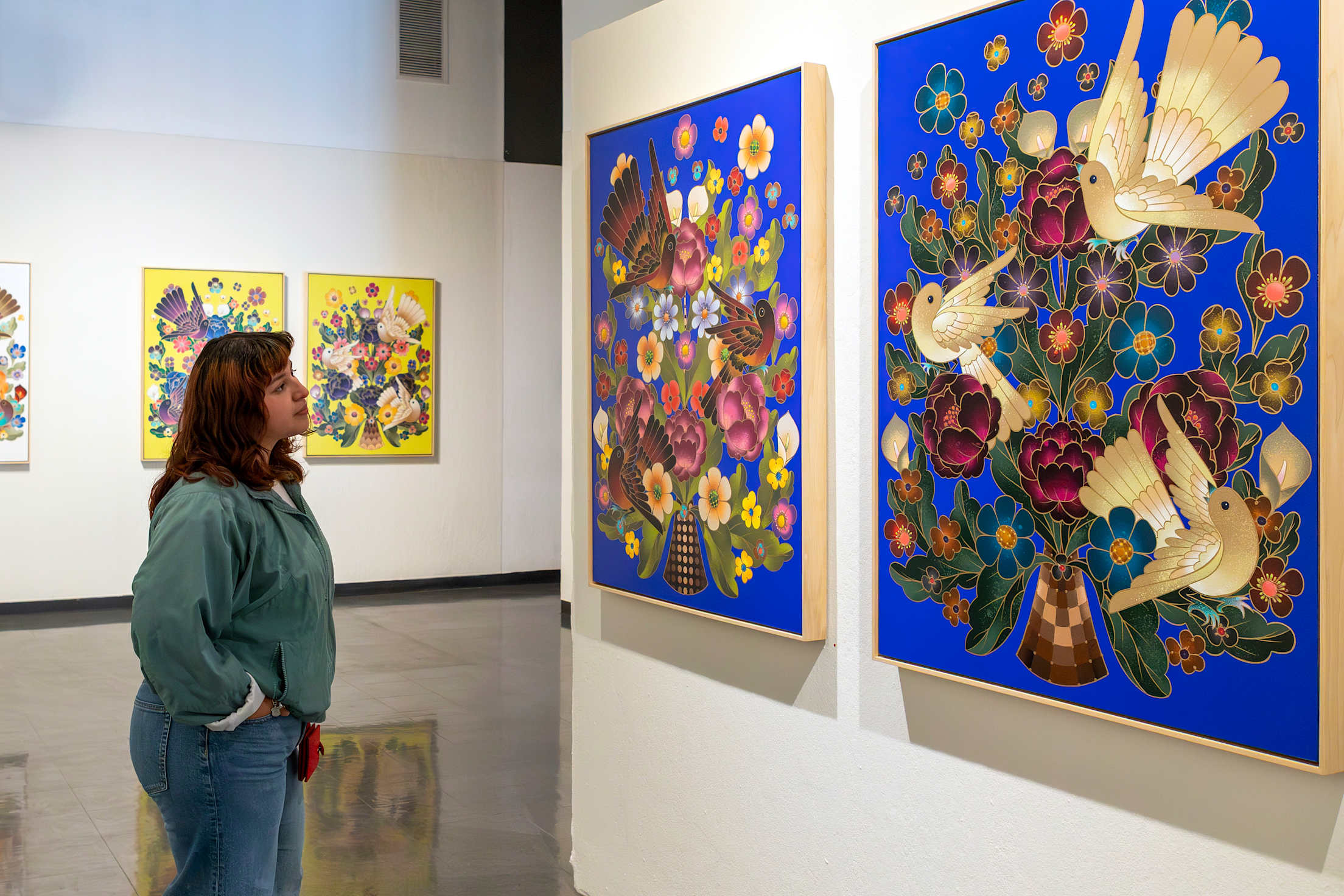a woman looks at a painting of birds in a museum