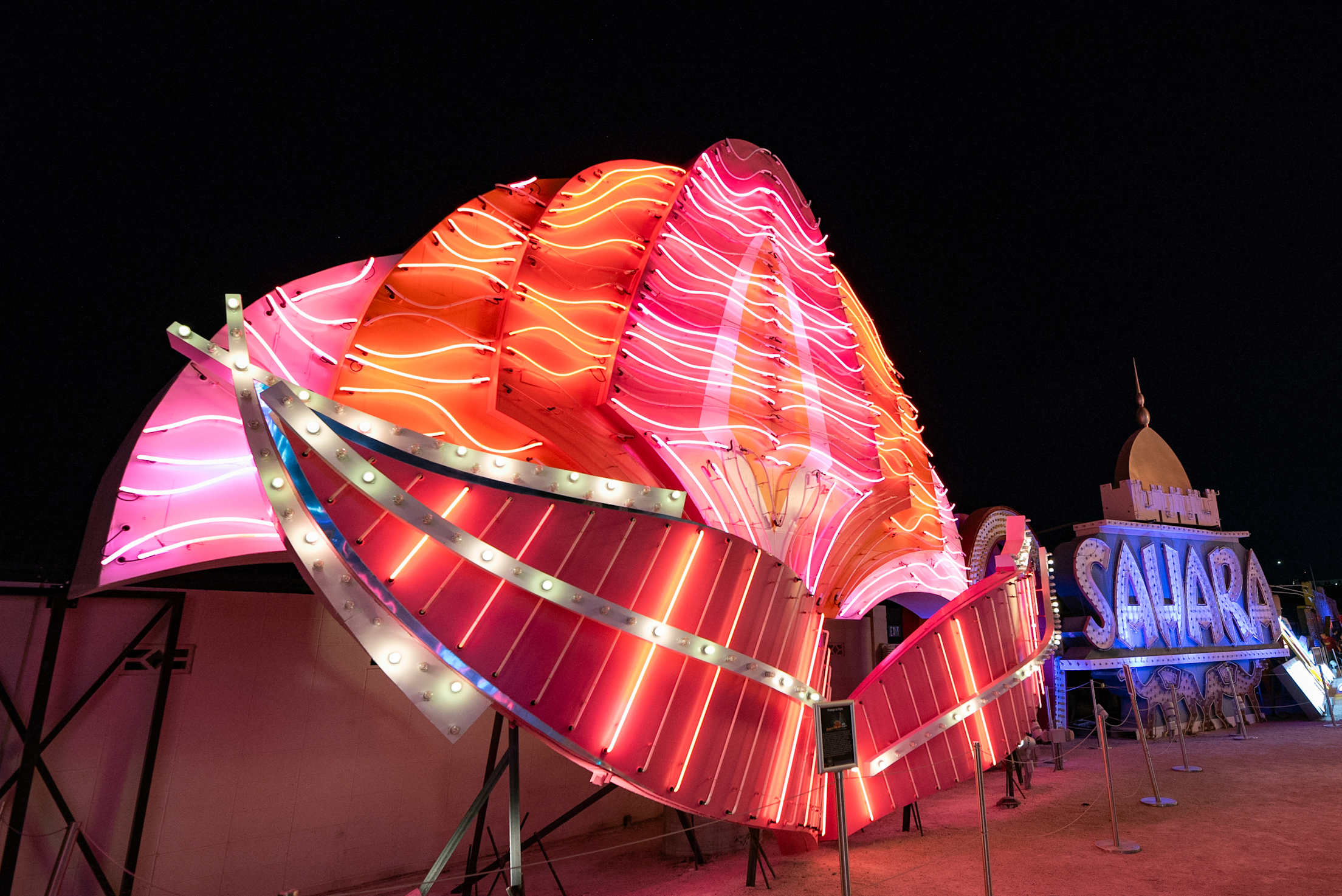 a neon sign that says 'sahara' is lit up in the desert