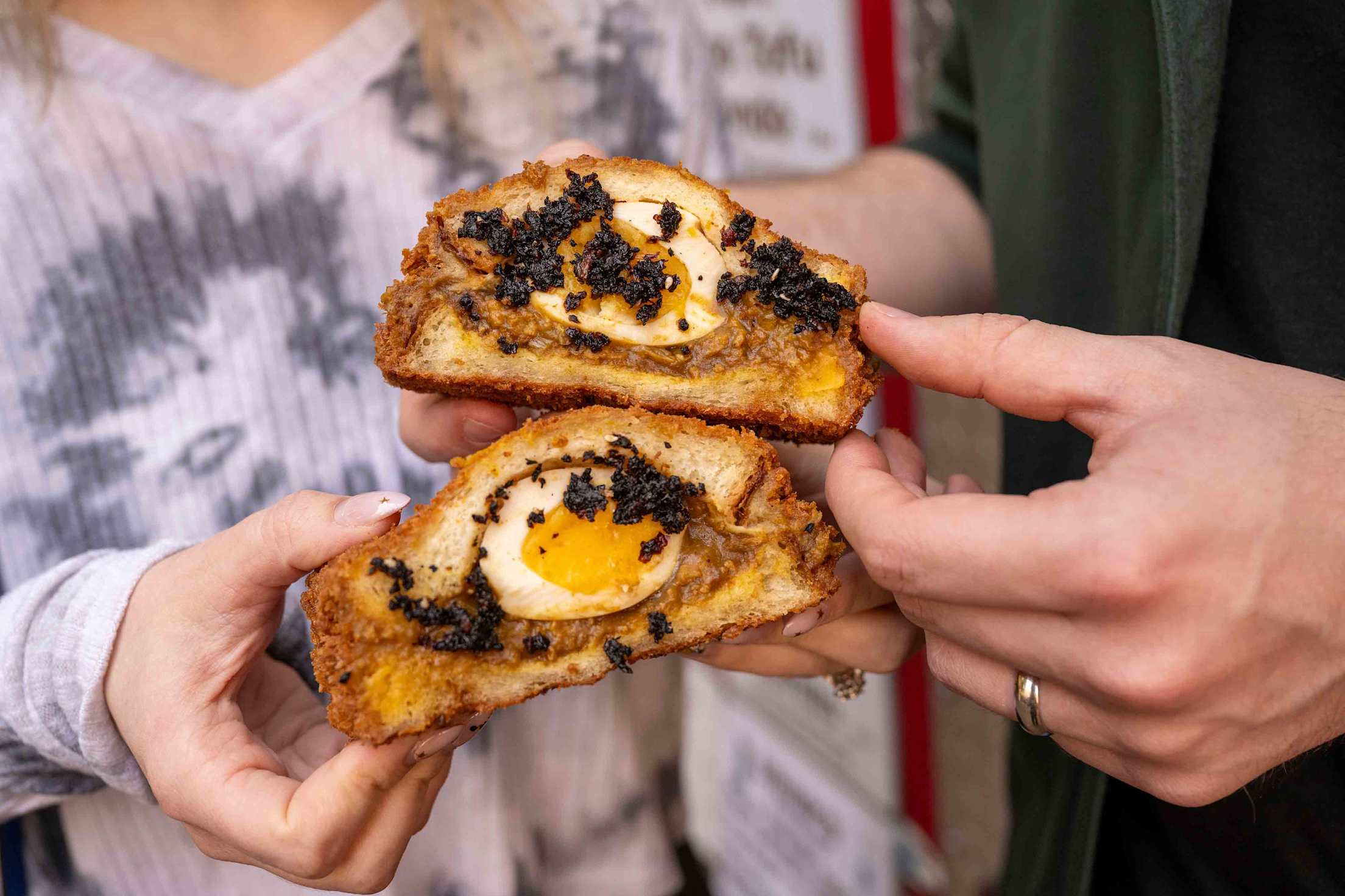 two people show off Japanese-style egg sandwiches cut in half