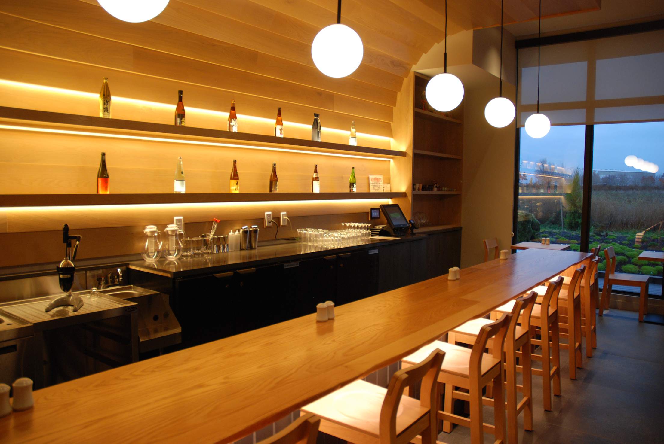 a sleek minimalist sake bar with wooden chairs