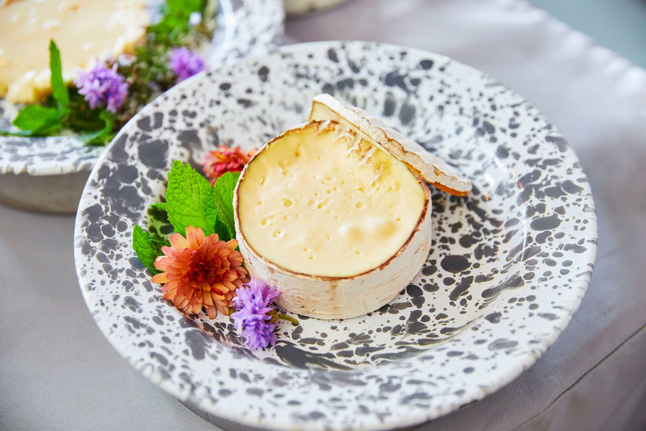 a beautiful circle of brie-like cheese on a plate with flowers