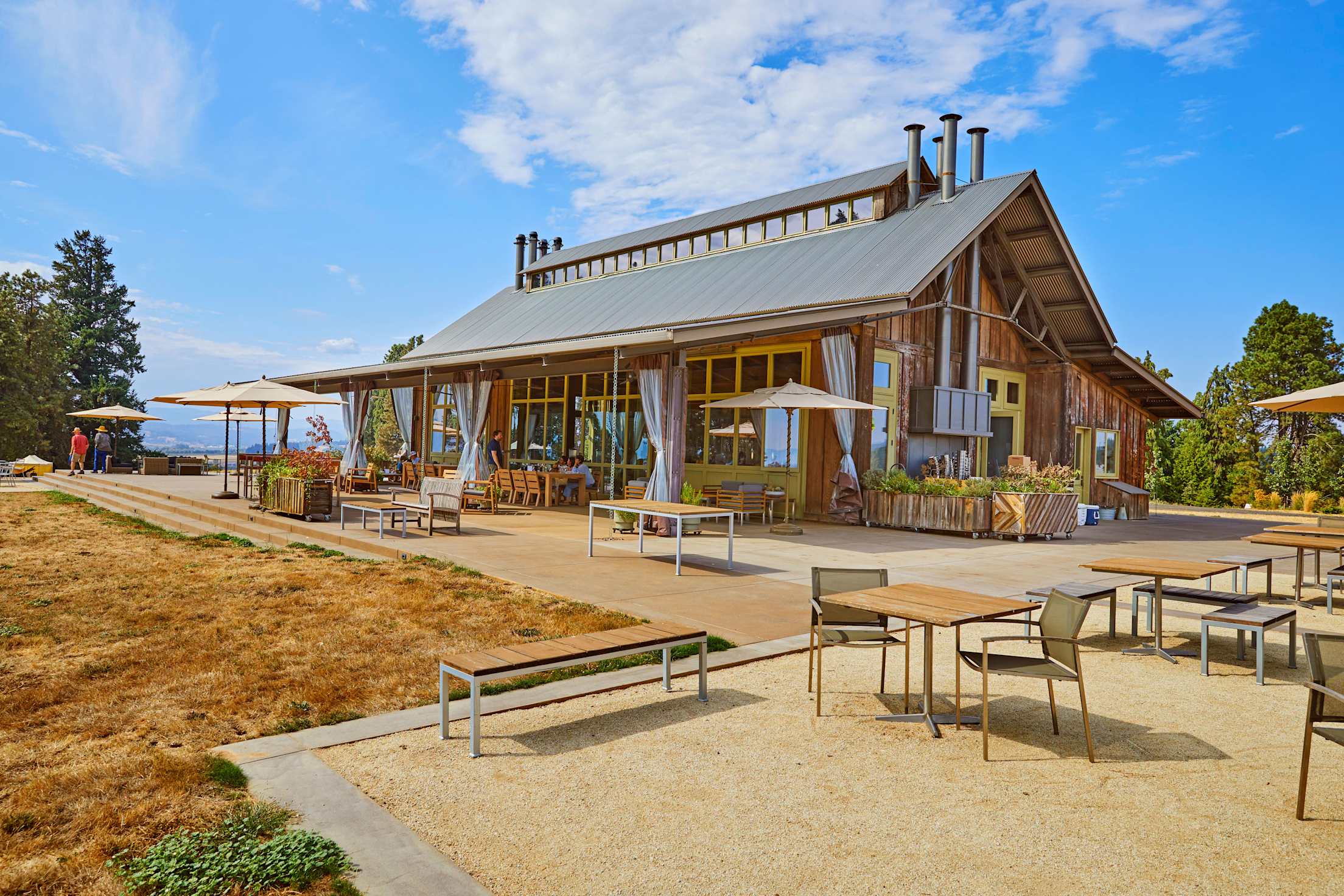 a restaurant with lots of windows and outside tables on a hillside