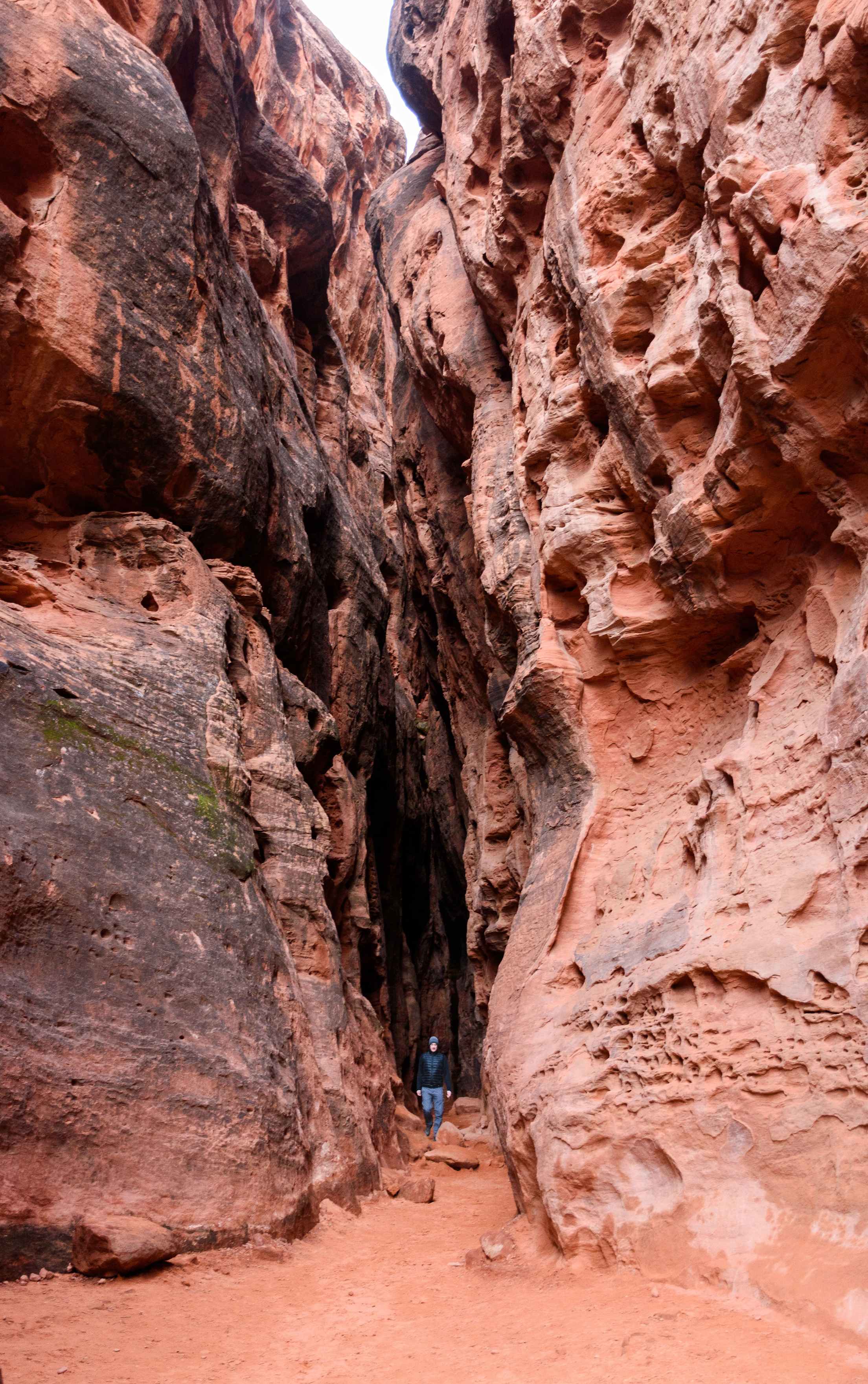 a hiker entering a red sandstone slot canyon