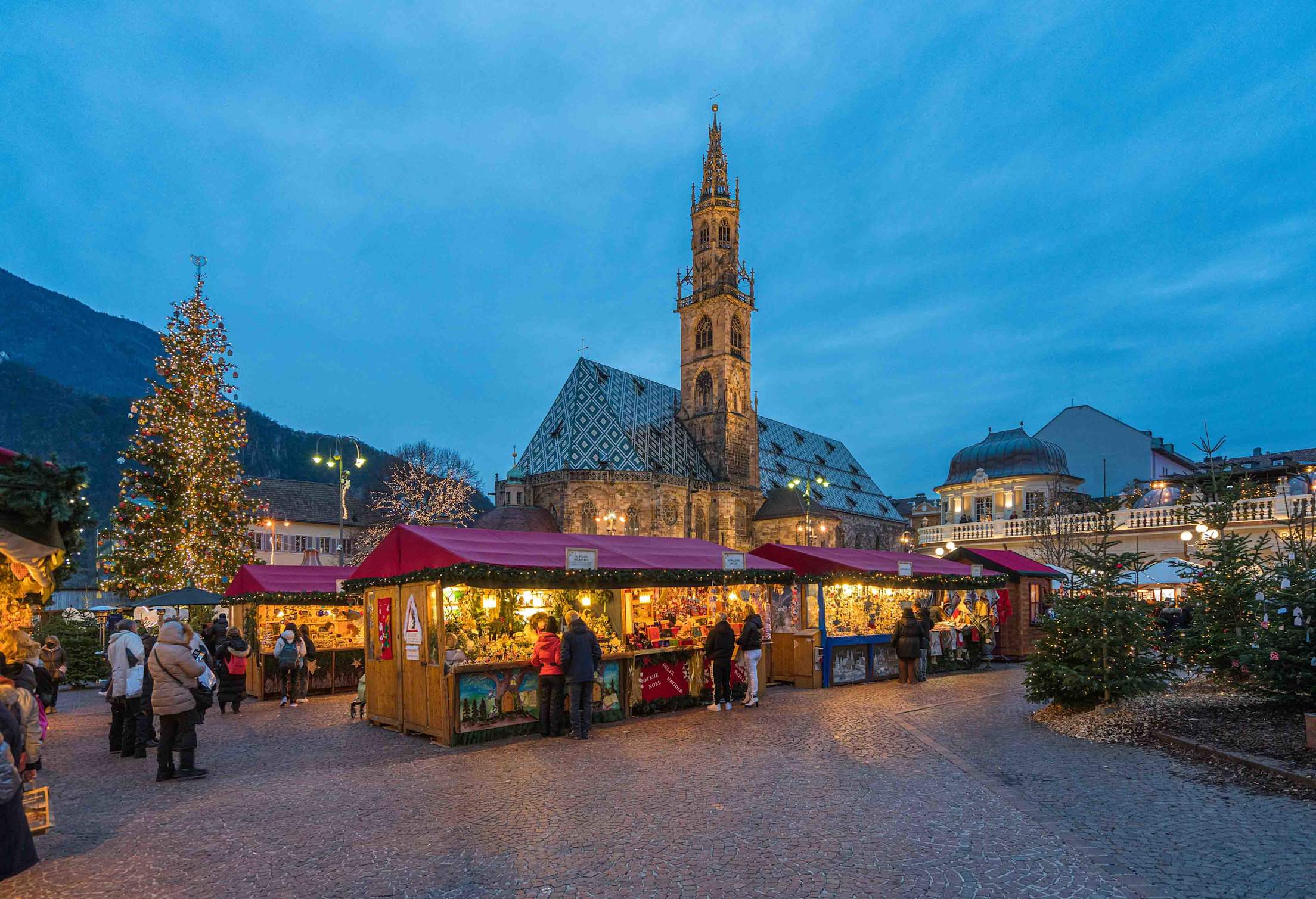 a festive Christmas market in front of a steeple in Italy