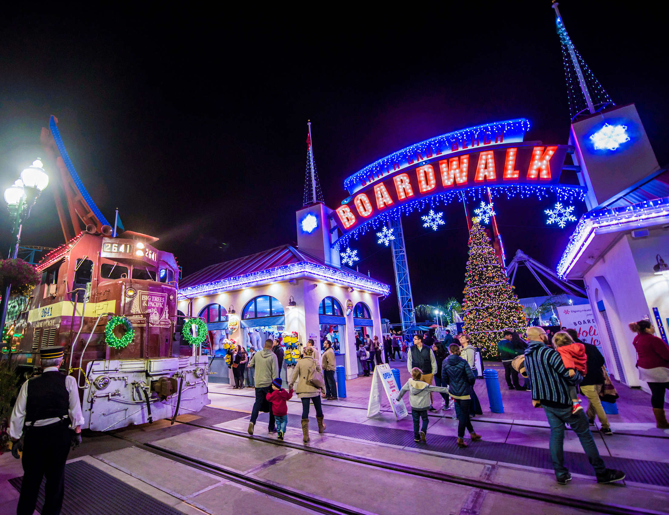 People walk past a decorate train at the Santa Cruz Beach Boardwalk Winter Wonderland.